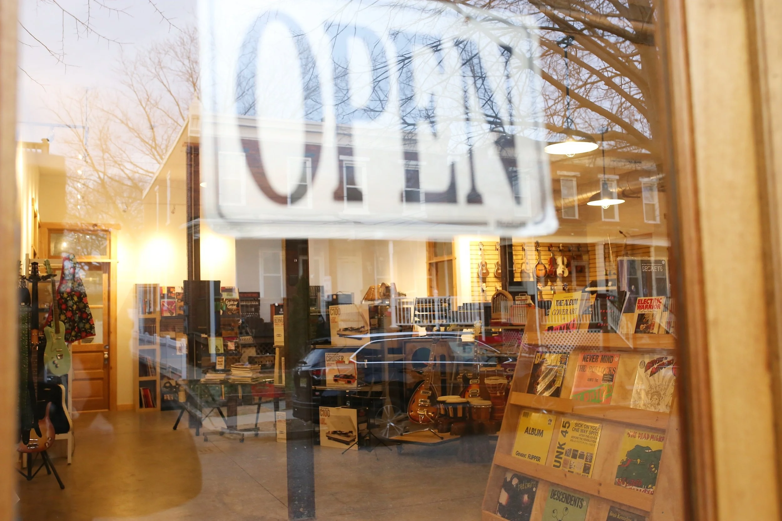 View into the Collingswood Music showroom through the front window with an open sign displayed