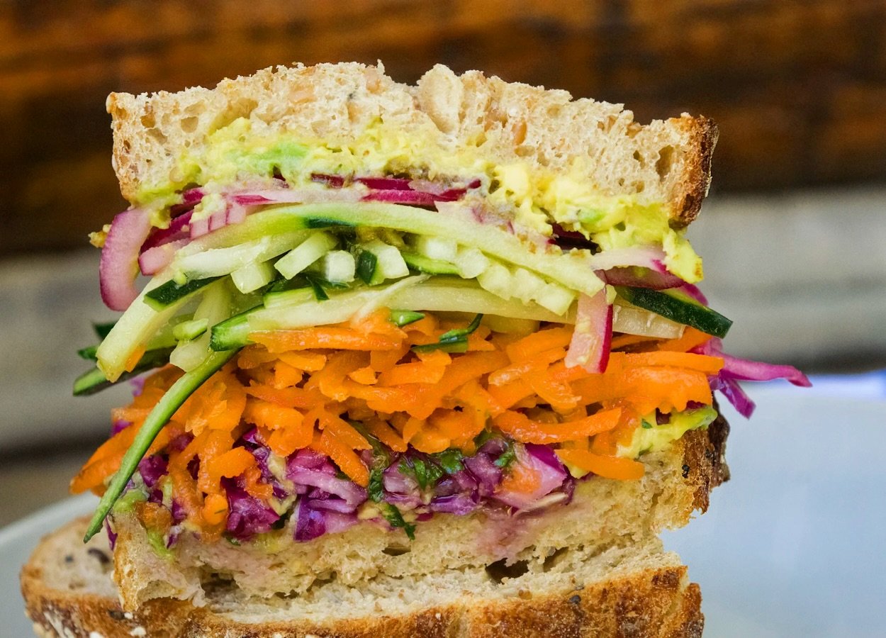Having a good day but want to make it even better? Order a great big veggie sandwich 🙌🏼
Imaging hummus, cucumbers, carrot-cabbage slaw, quick pickled red onions, lemon avocado mash, homemade lemon-herb vin, on locally made bread. It&rsquo;s a must 