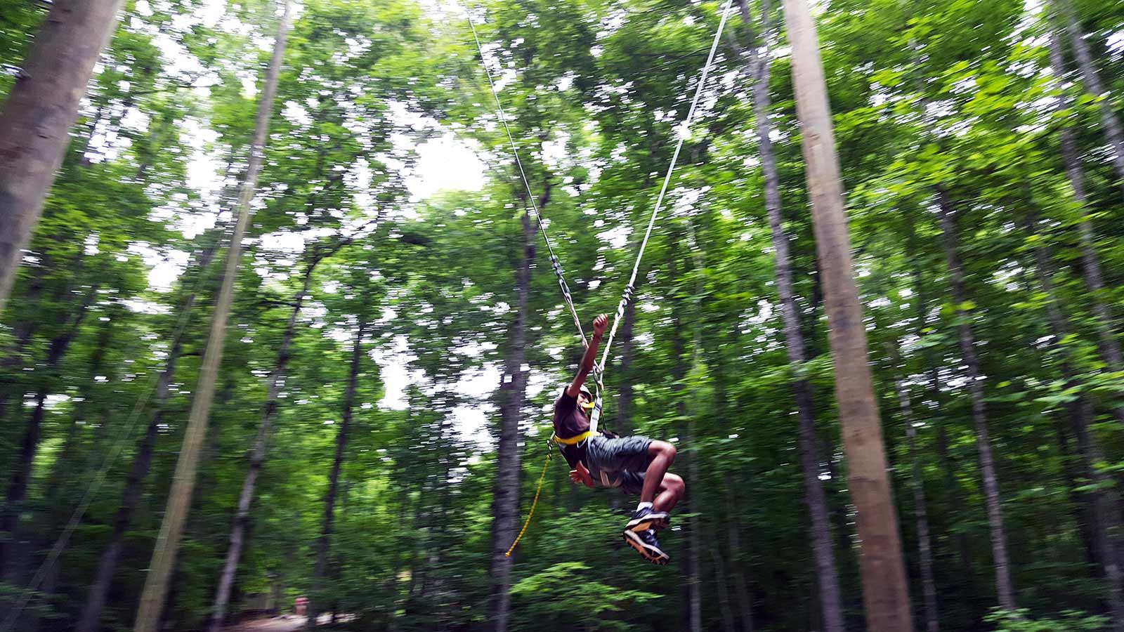 Summer Camper on the zip line in motion - NaCoMe Camp & Conference Center