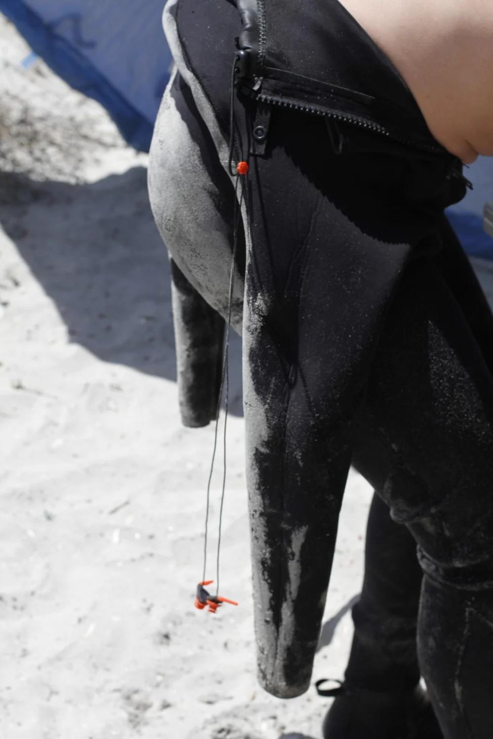 Comes with a teather that can be attached to somewhere on your wetsuit. Works best if attached to somewhere near neck chest area, a place with the least tension. 