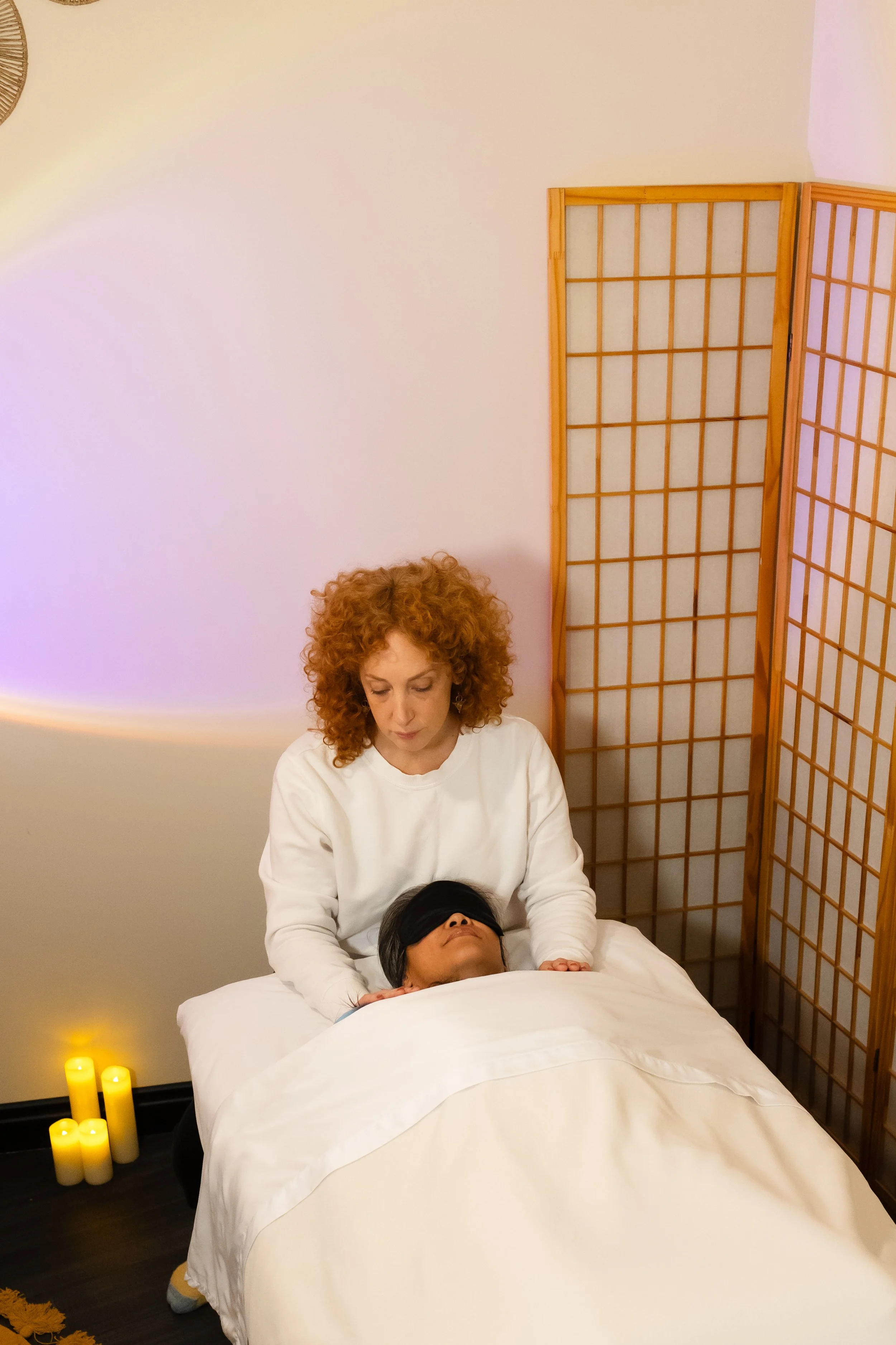 energy healer has her hands placed on shoulders giving Reiki and intuitive guidance