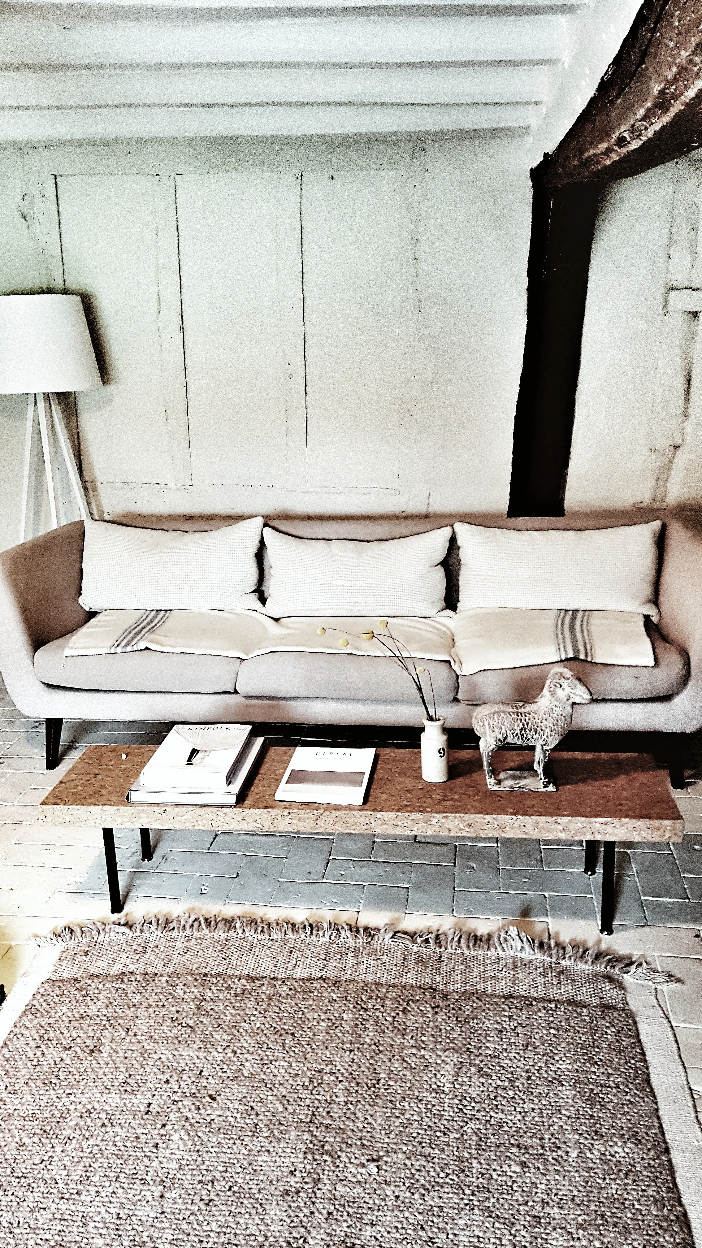 The living room at the cottage was painted in neutral colours with texture and warmth added through touches such as the jute rug and woolen cushions and blankets