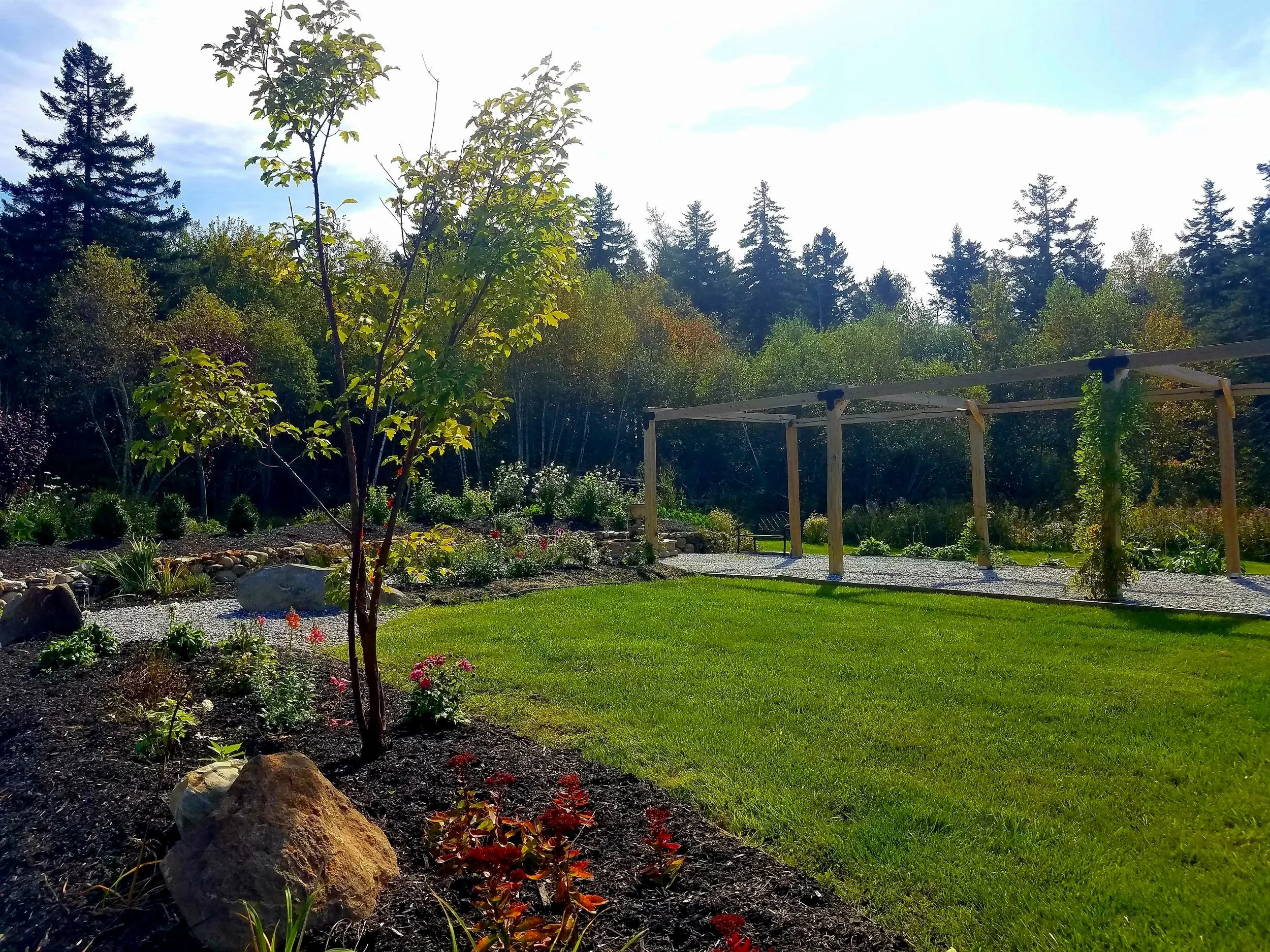 A overlooking view of one of our many gardens at 19 Birch Lane in the distance you can our pavilion with Wisteria growing on it.