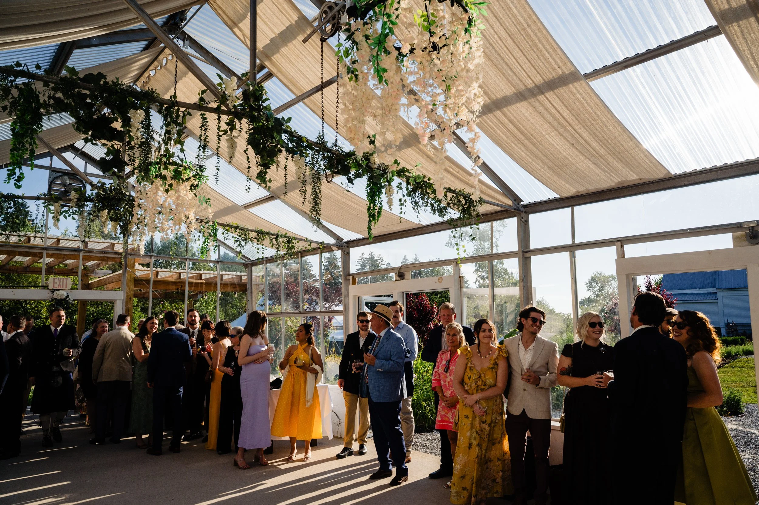 Wedding guests celebrating inside the greenhouse at 19 Birch Lane on a beautiful summer afternoon.