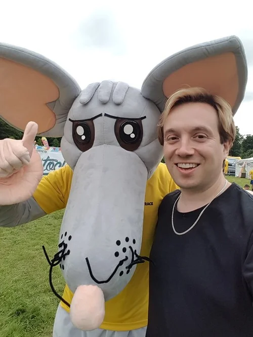 Matthew Garrett with the Rat Race mascot while performing at Boughton House near Kettering