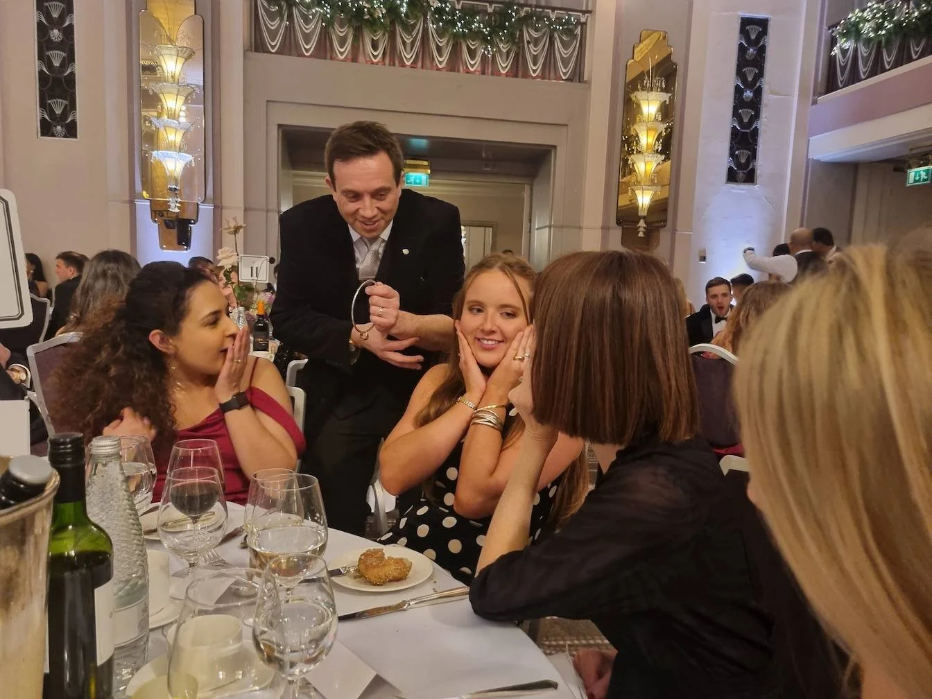 Close-up magician performing for huests at a formal family event