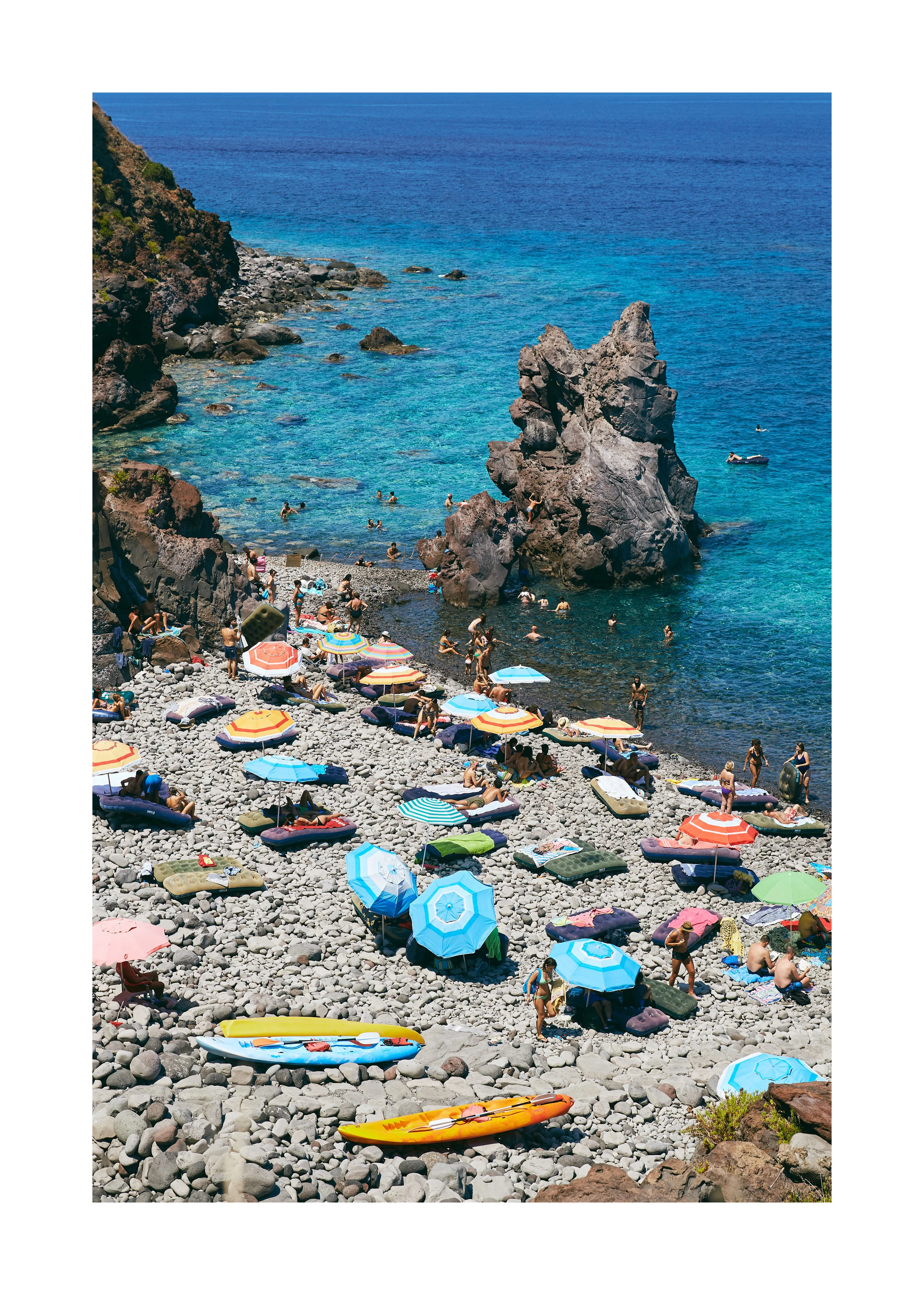 Framed beach scene of Malfa, Salina, Italy with colorful umbrellas, kayaks, and clear blue water.