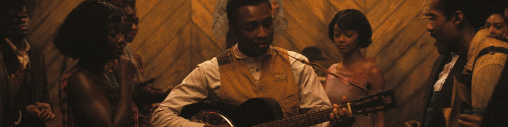 Miles Caton plays guitar surrounded  by admiring watchers in Sinners.