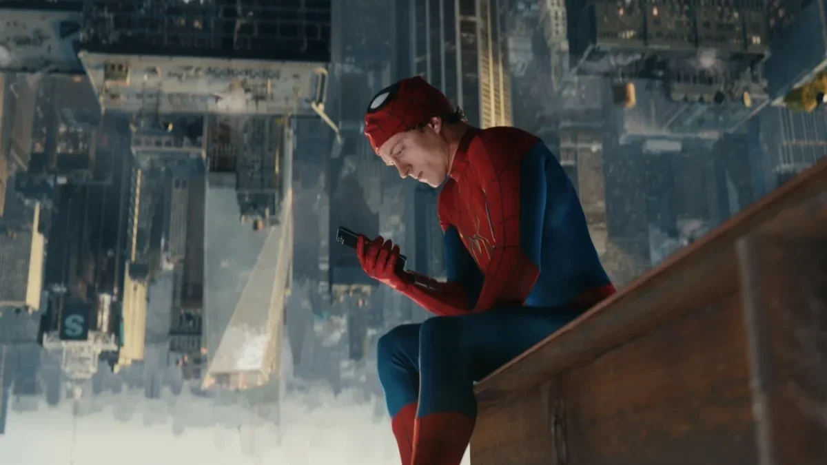 Peter Parker (played by Tom Holland) as Spider-Man looks sadly at his phone while hanging upside down in the film 'Spider-Man: A Brand New Day.'