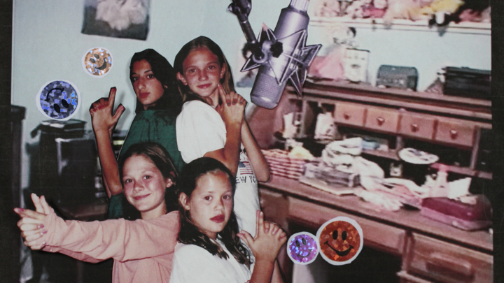 Photograph of four young girls posing behind a microphone.