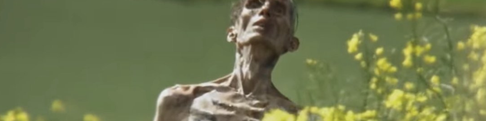 An emaciated zombie lifts its head in 28 Years Later.