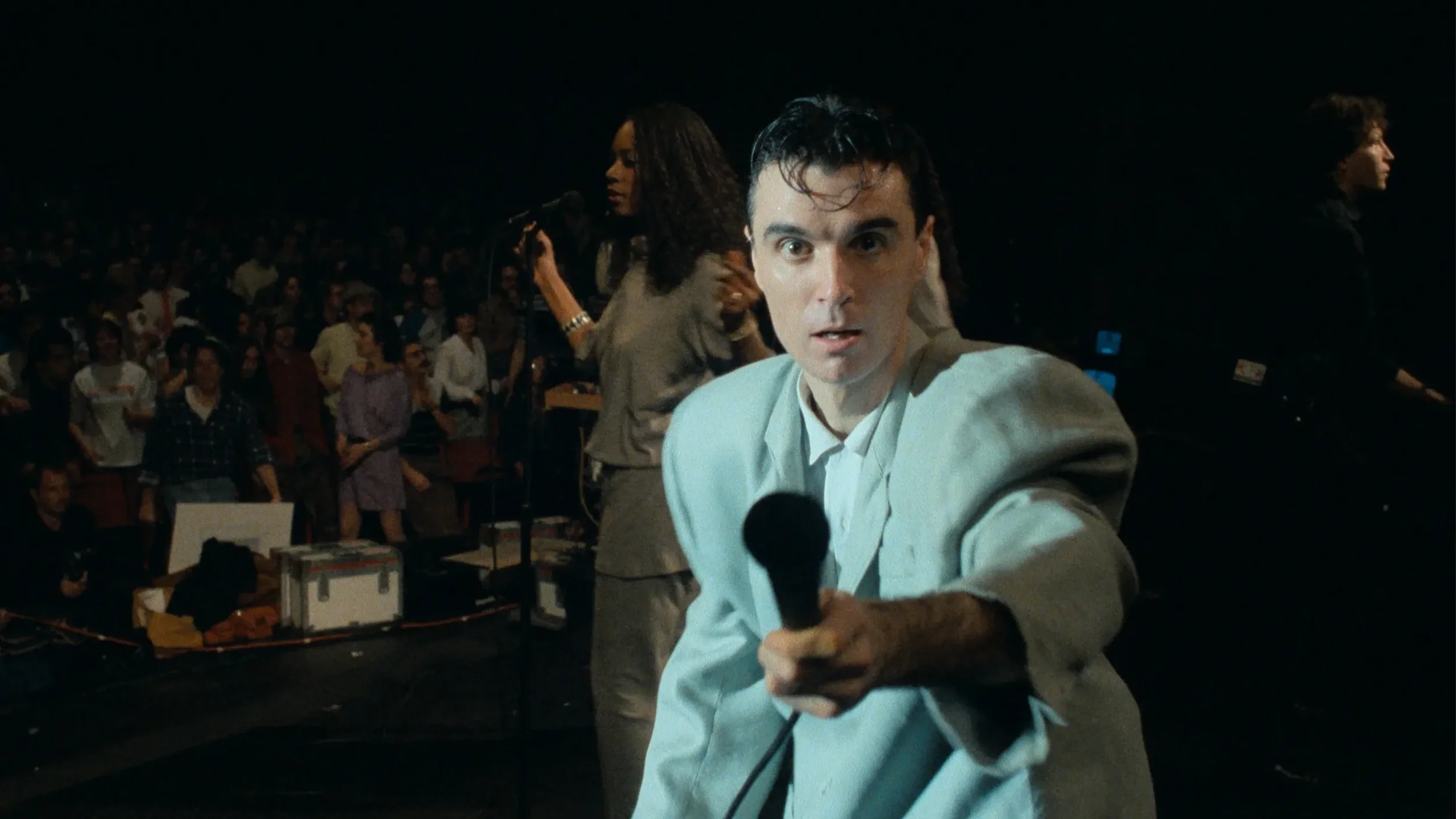 David Byrne points a microphone towards the viewer in the concert film, 'Stop Making Sense.'