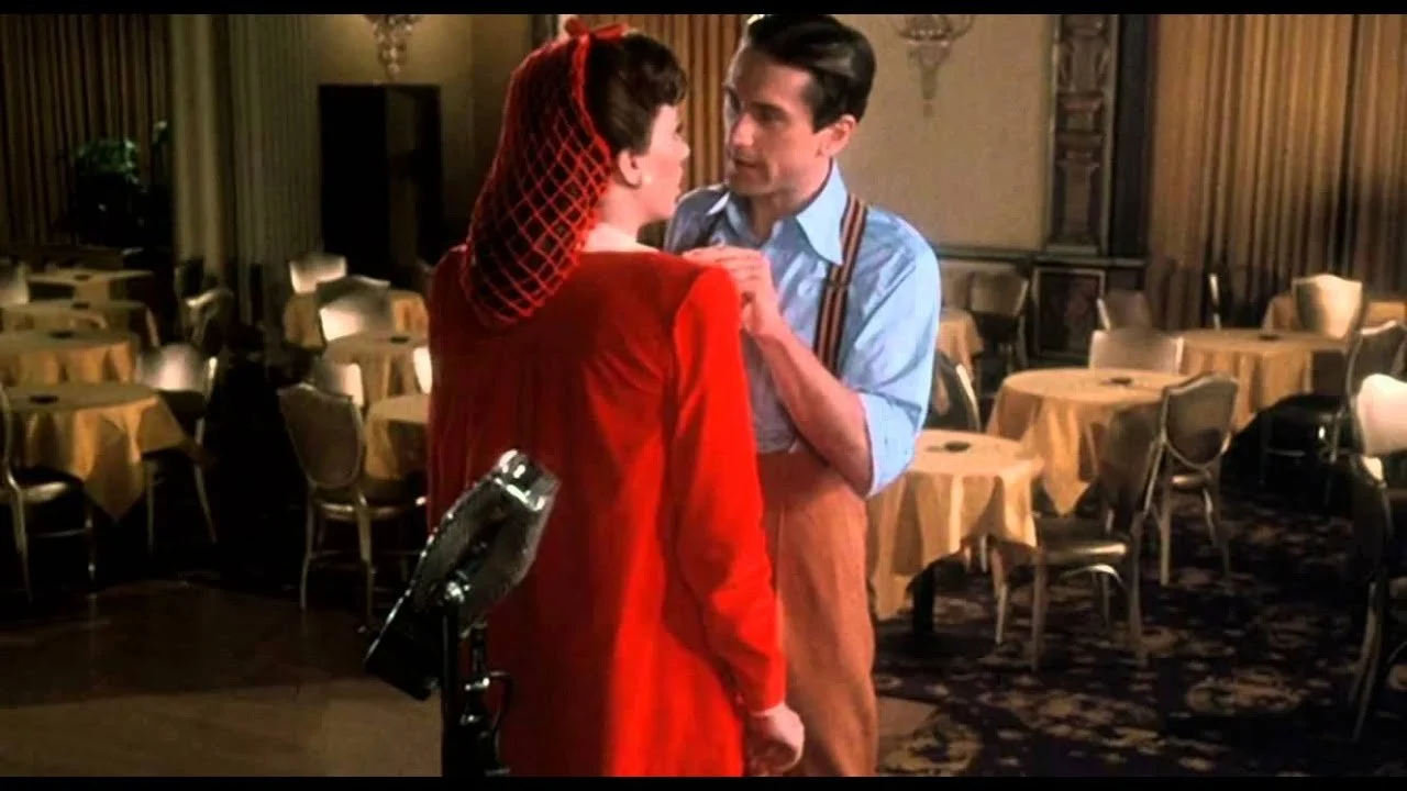 Robert De Niro stands close to Liza Minnelli in a confrontational pose. They stand in an empty night club.