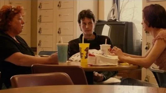 Martha, Kyle, and Rose all sit together at a table for lunch in their work break room in the movie Bubble.