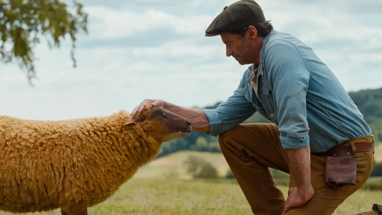 Lily the sheep (voiced by Julia-Louis Dreyfus) is pet on the head by sheep farmer George Hardy (played by Hugh Jackman) in The Sheep Detectives.