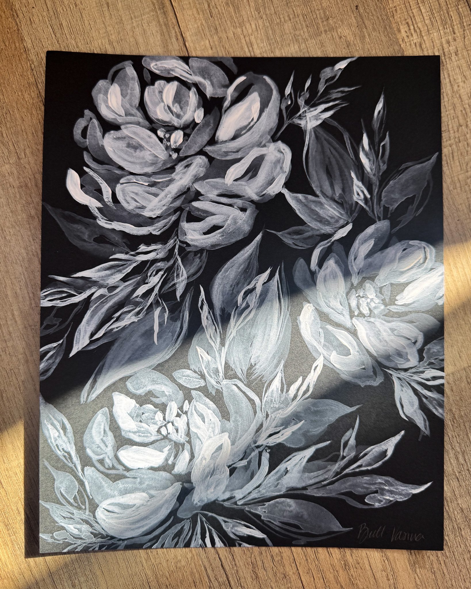 Floral painting on black paper in a beam of sunlight