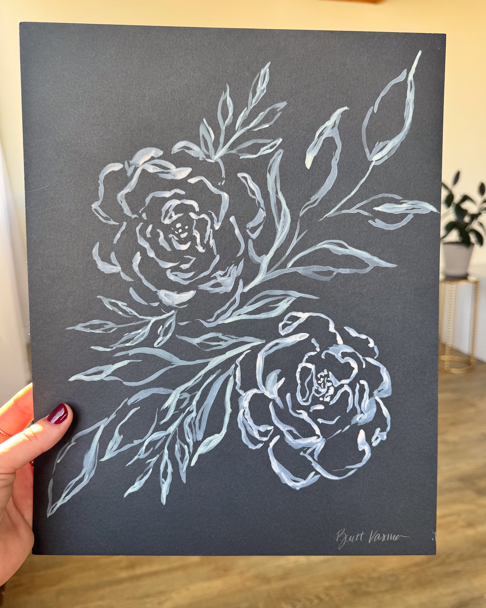 Hand holding an original acrylic floral painting on black paper