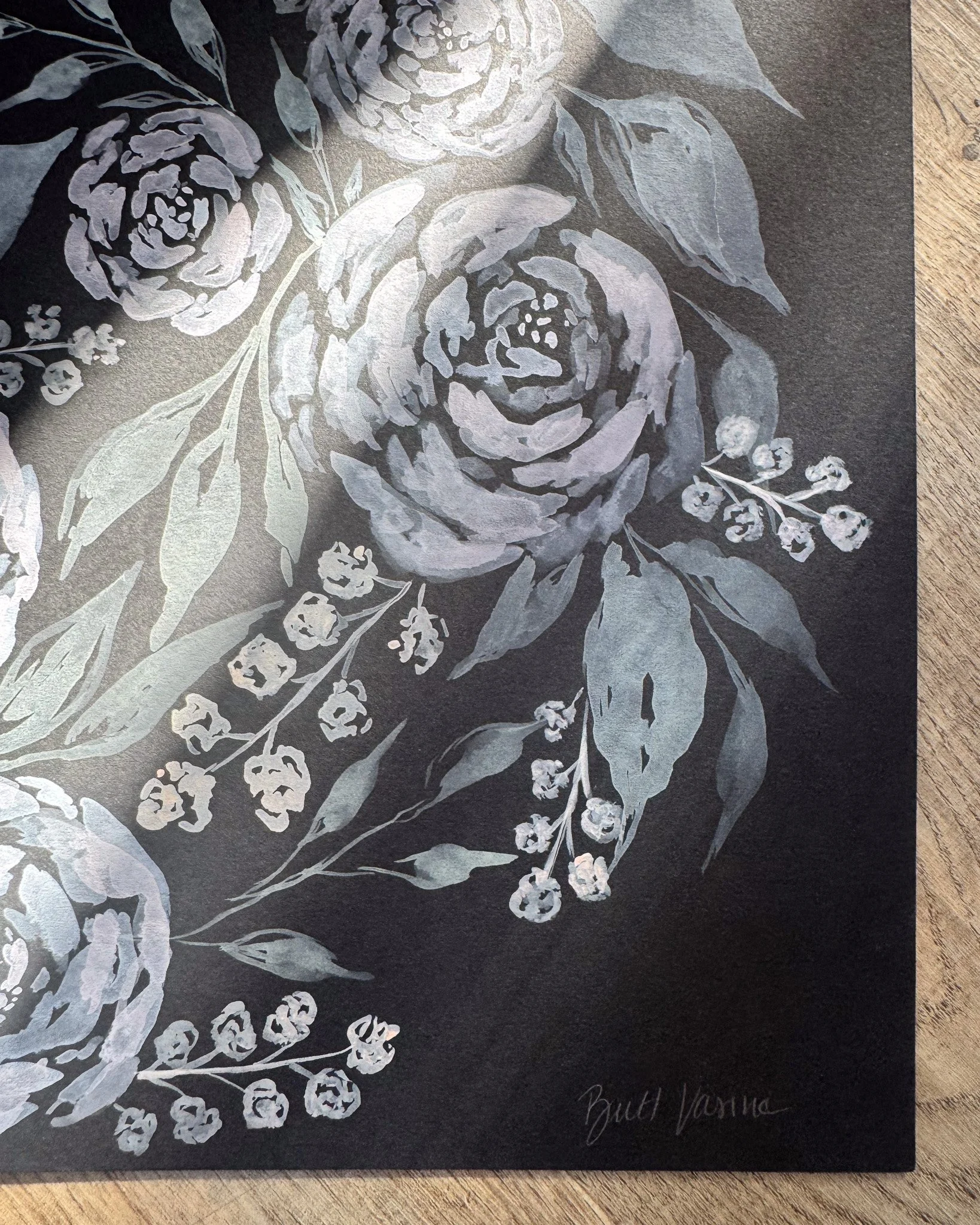 Close-up of white acrylic petals and signature on black paper