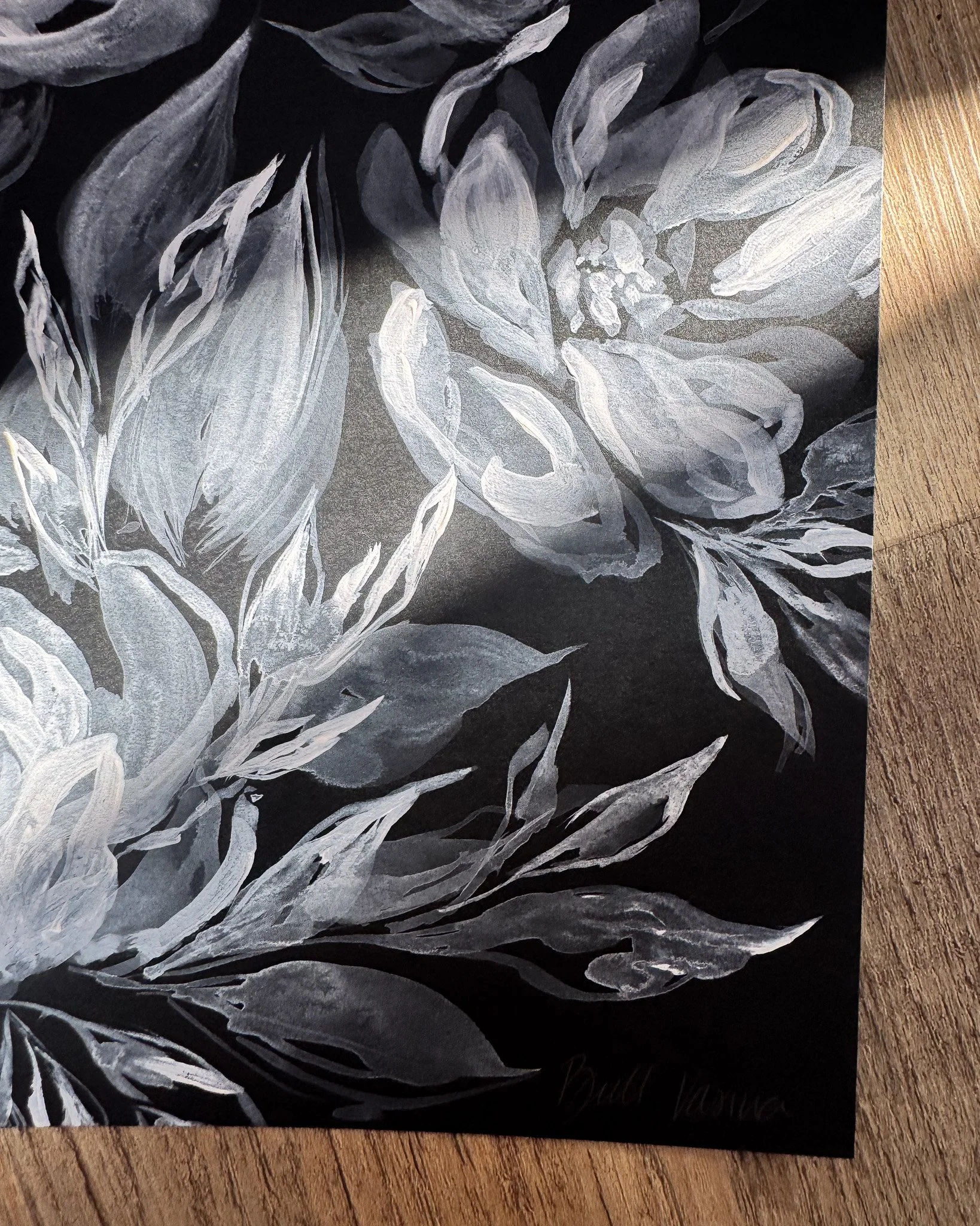 Close-up of white acrylic petals and signature on black paper