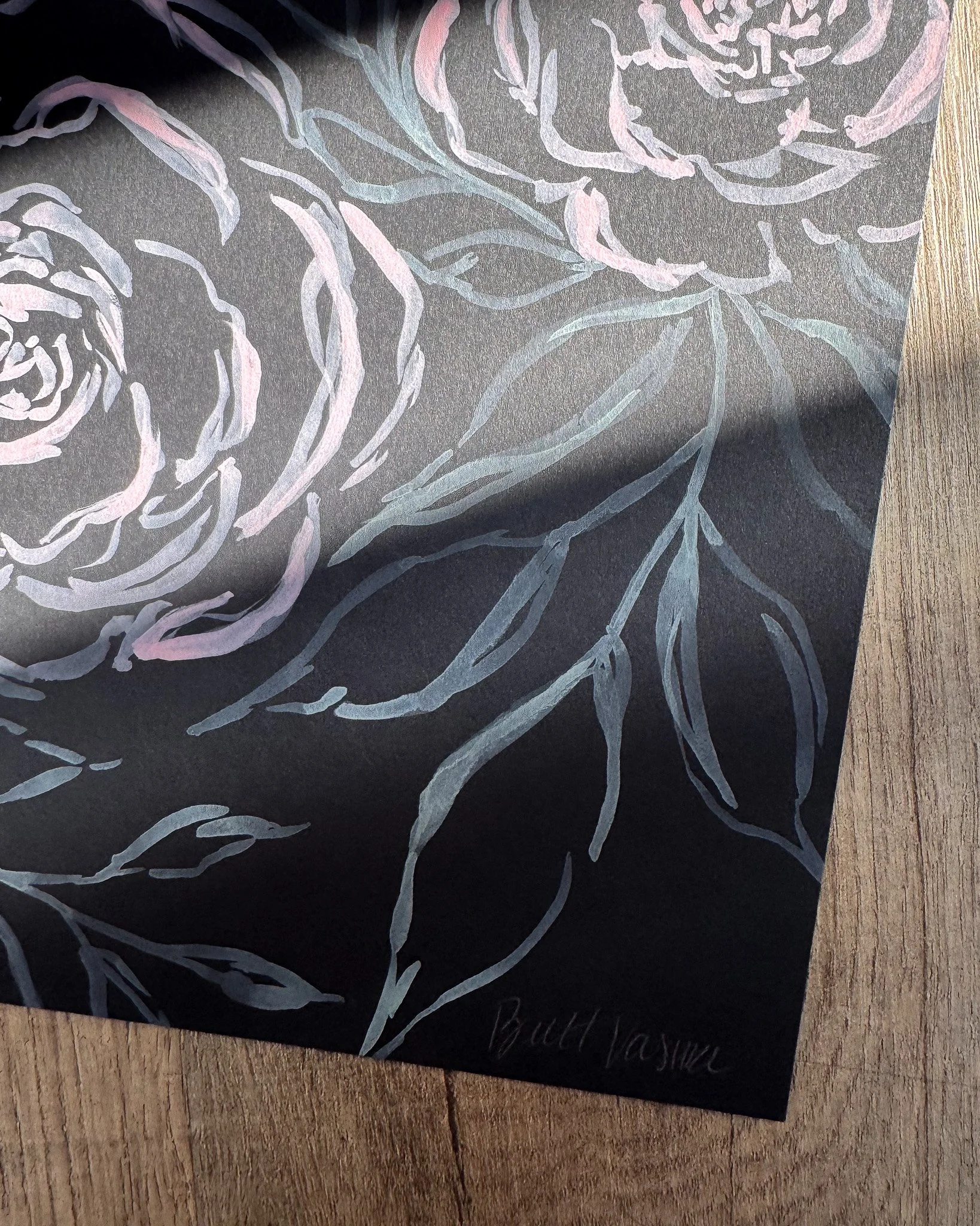 Close-up of white acrylic petals and signature on black paper