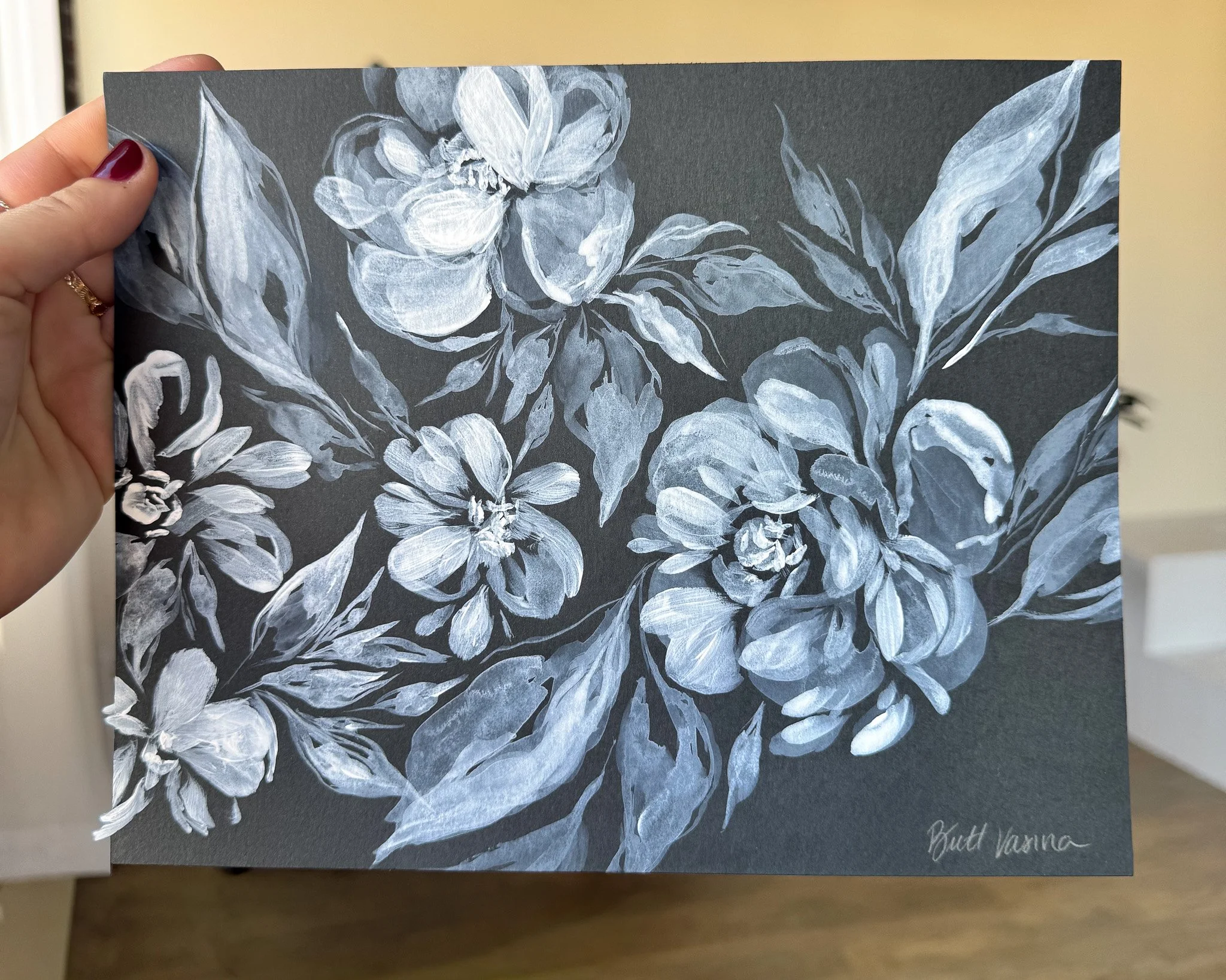 Hand holding an original acrylic floral painting on black paper