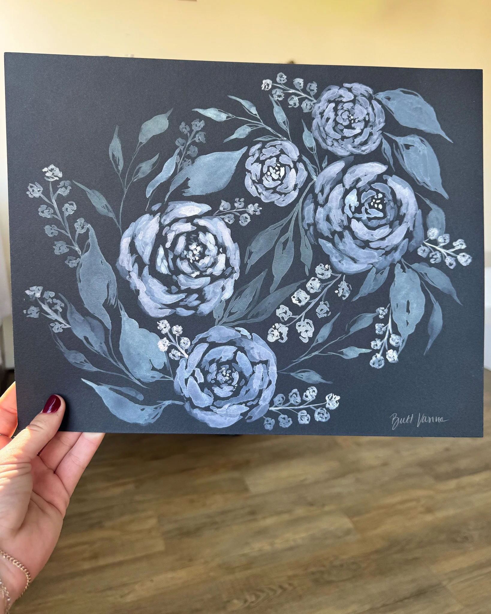 Hand holding an original acrylic floral painting on black paper