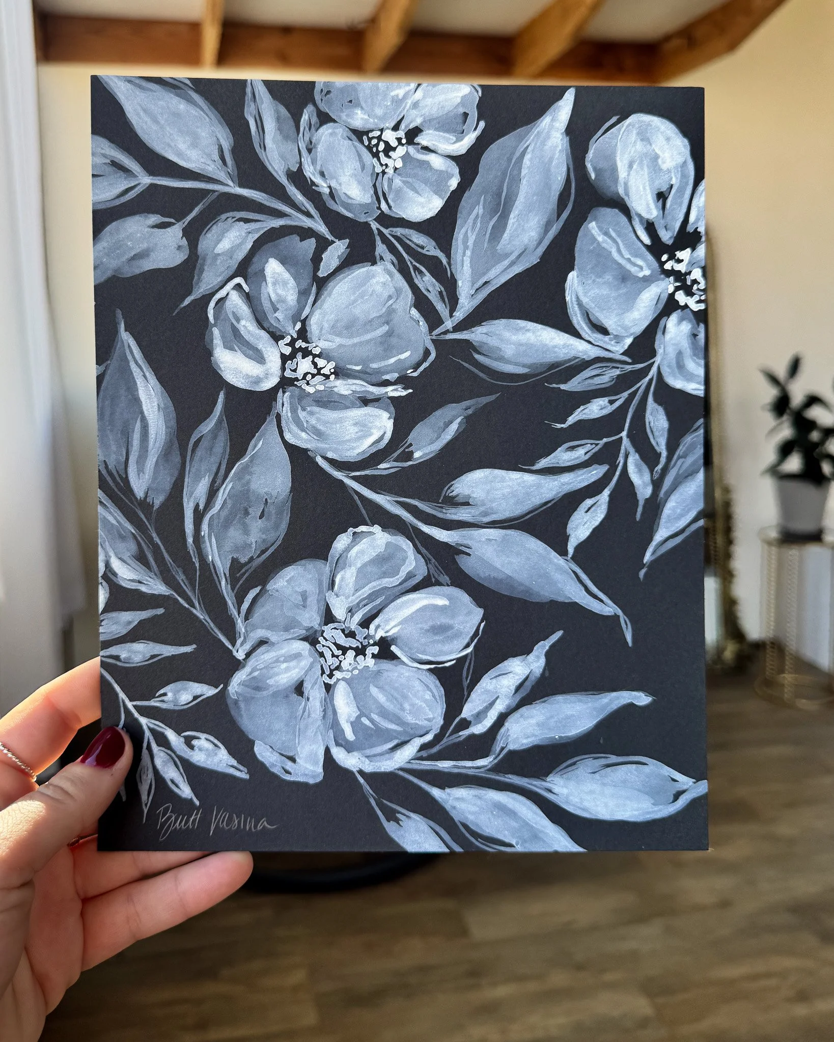 Hand holding an original acrylic floral painting on black paper