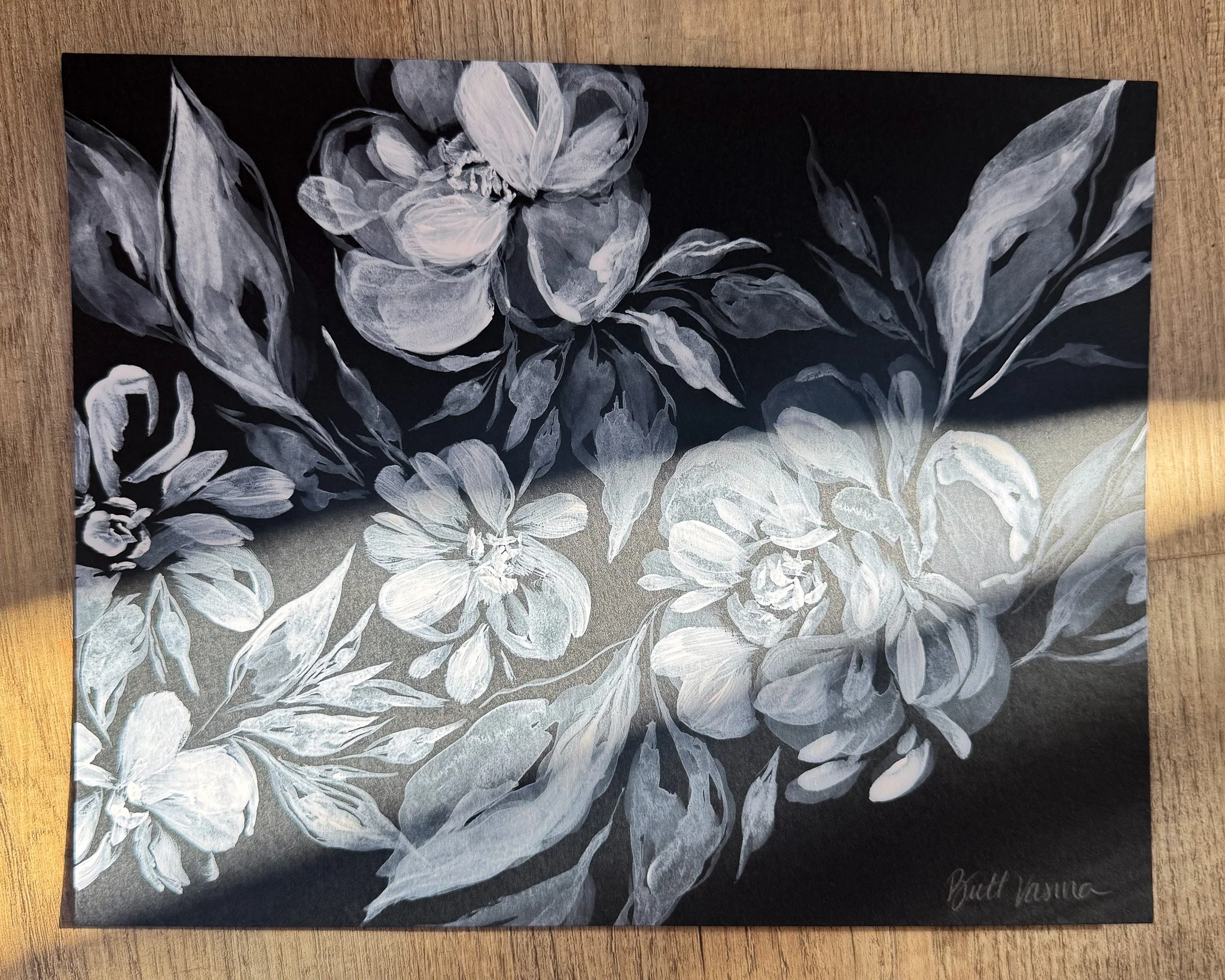 Floral painting on black paper in a beam of sunlight