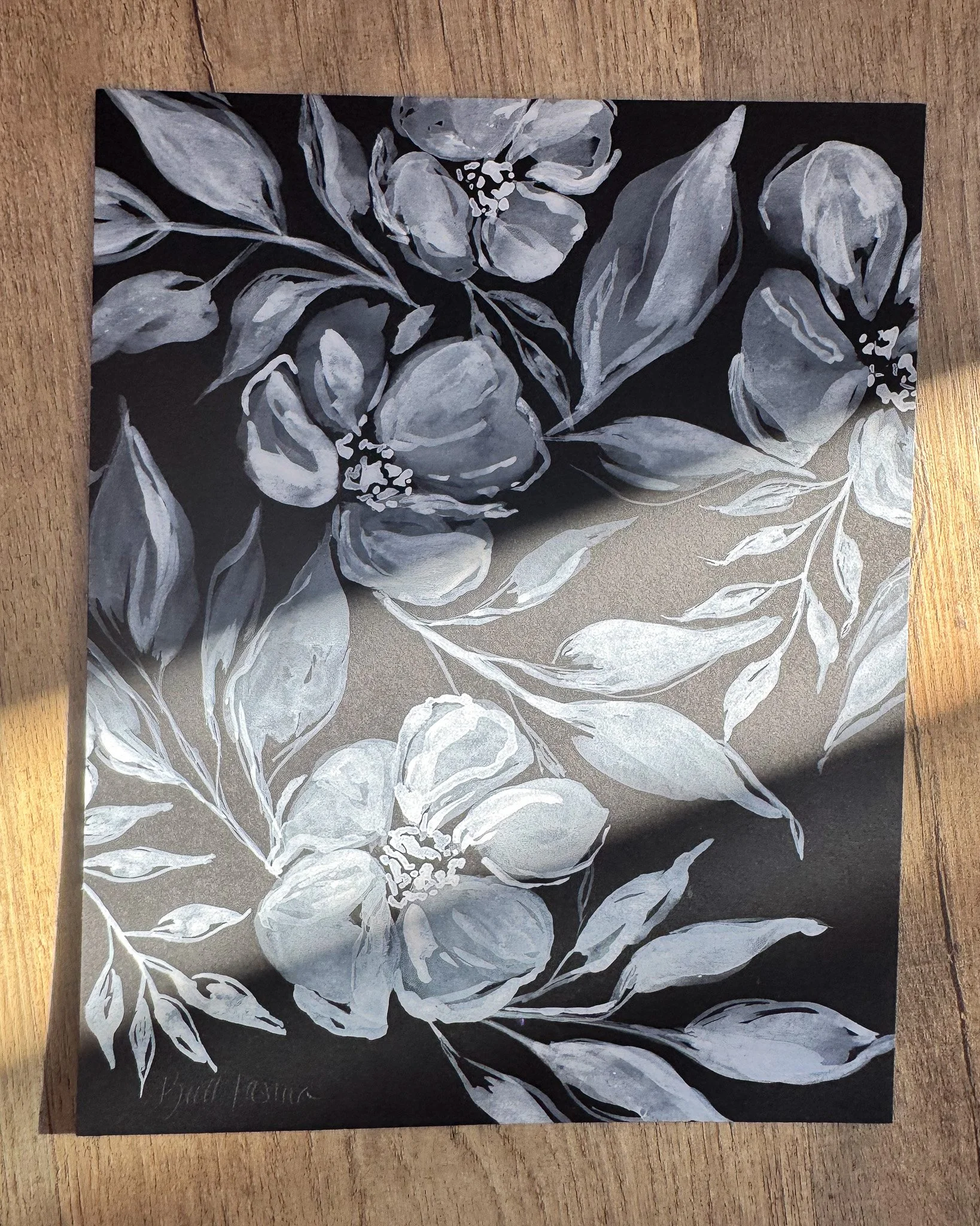 Floral painting on black paper in a beam of sunlight