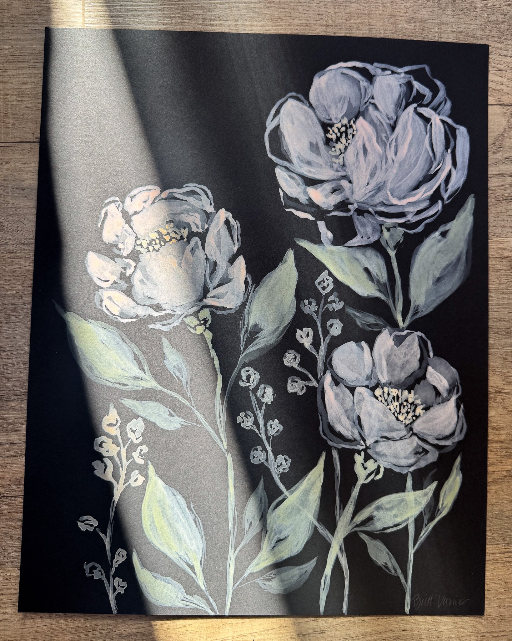 Floral painting on black paper in a beam of sunlight