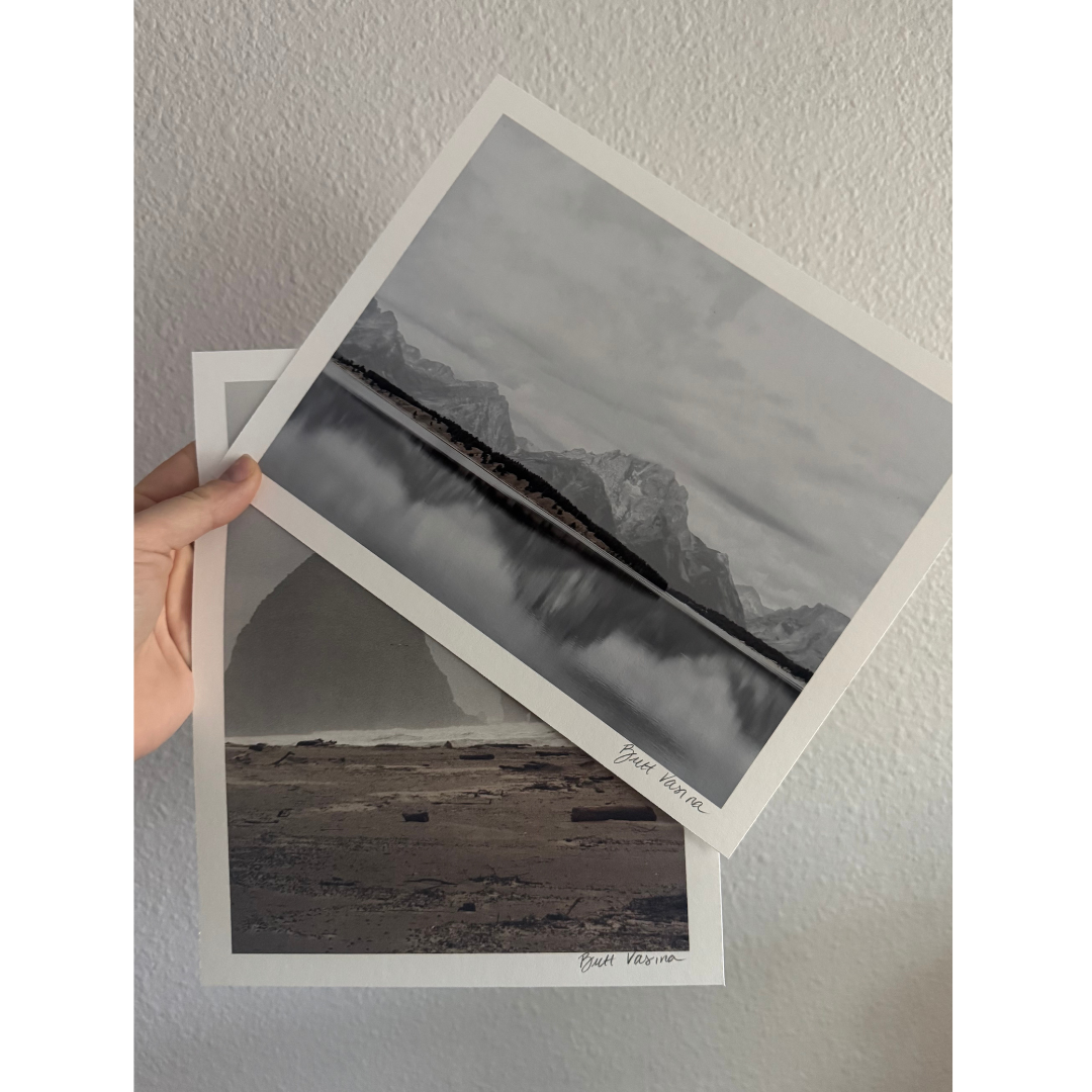 Hand holding two fine art prints with a matte finish and border by Britt Vasina