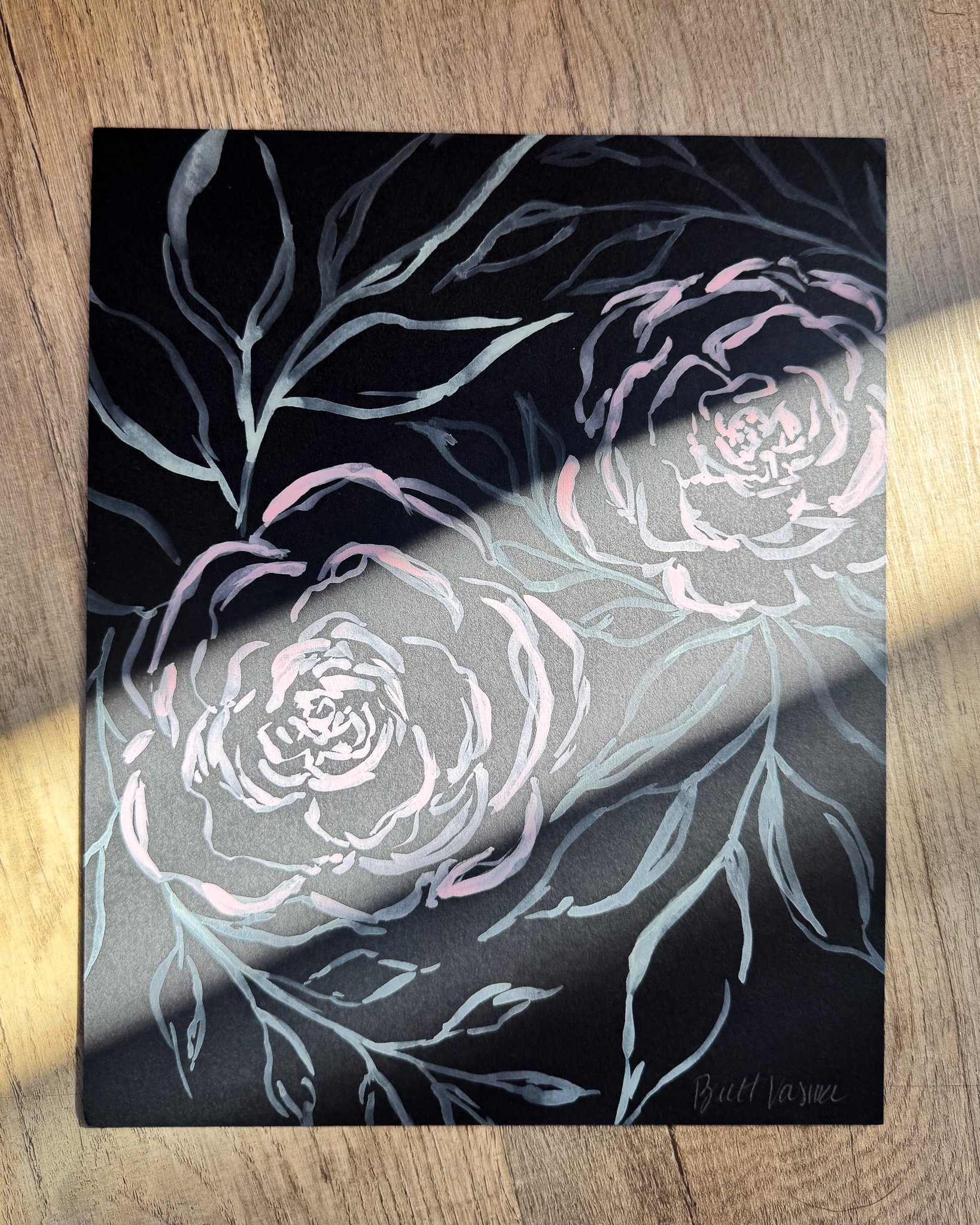 Floral painting on black paper in a beam of sunlight