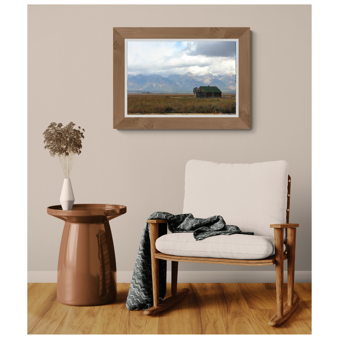 Storm Over Mormon Row Barn, Grand Teton, fine art print, framed and matted, styled in a room next to a chair, Britt Vasina Studio