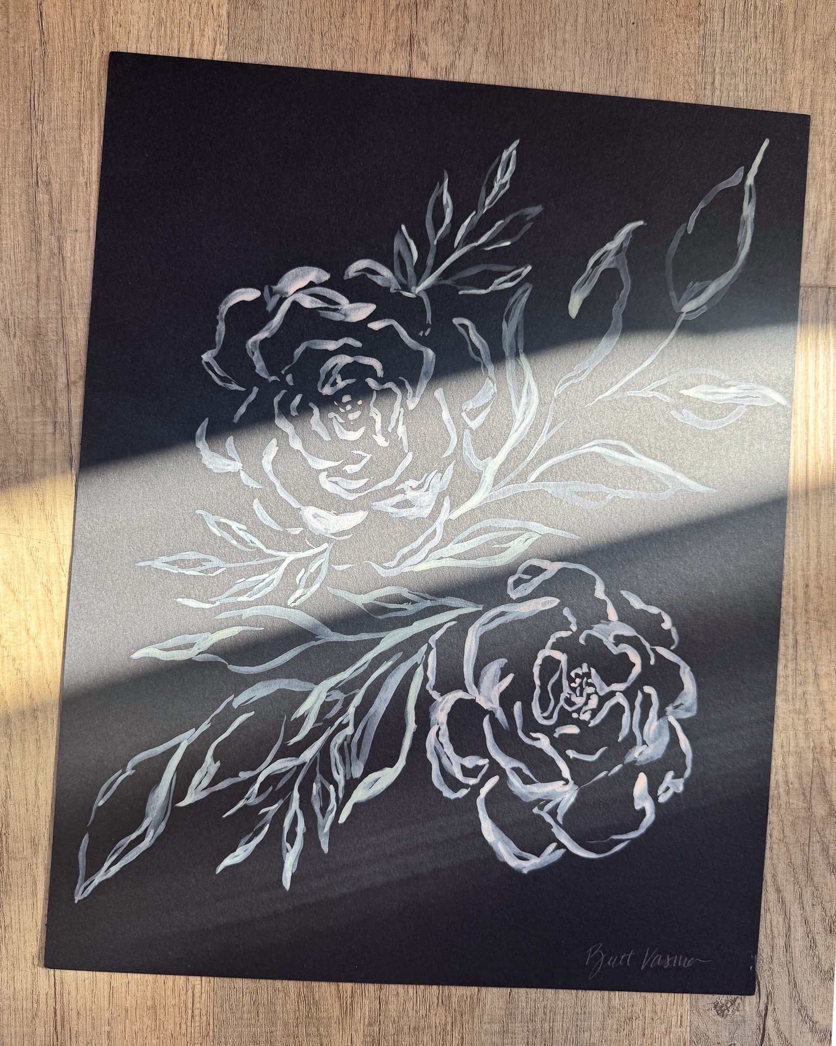 Floral painting on black paper in a beam of sunlight