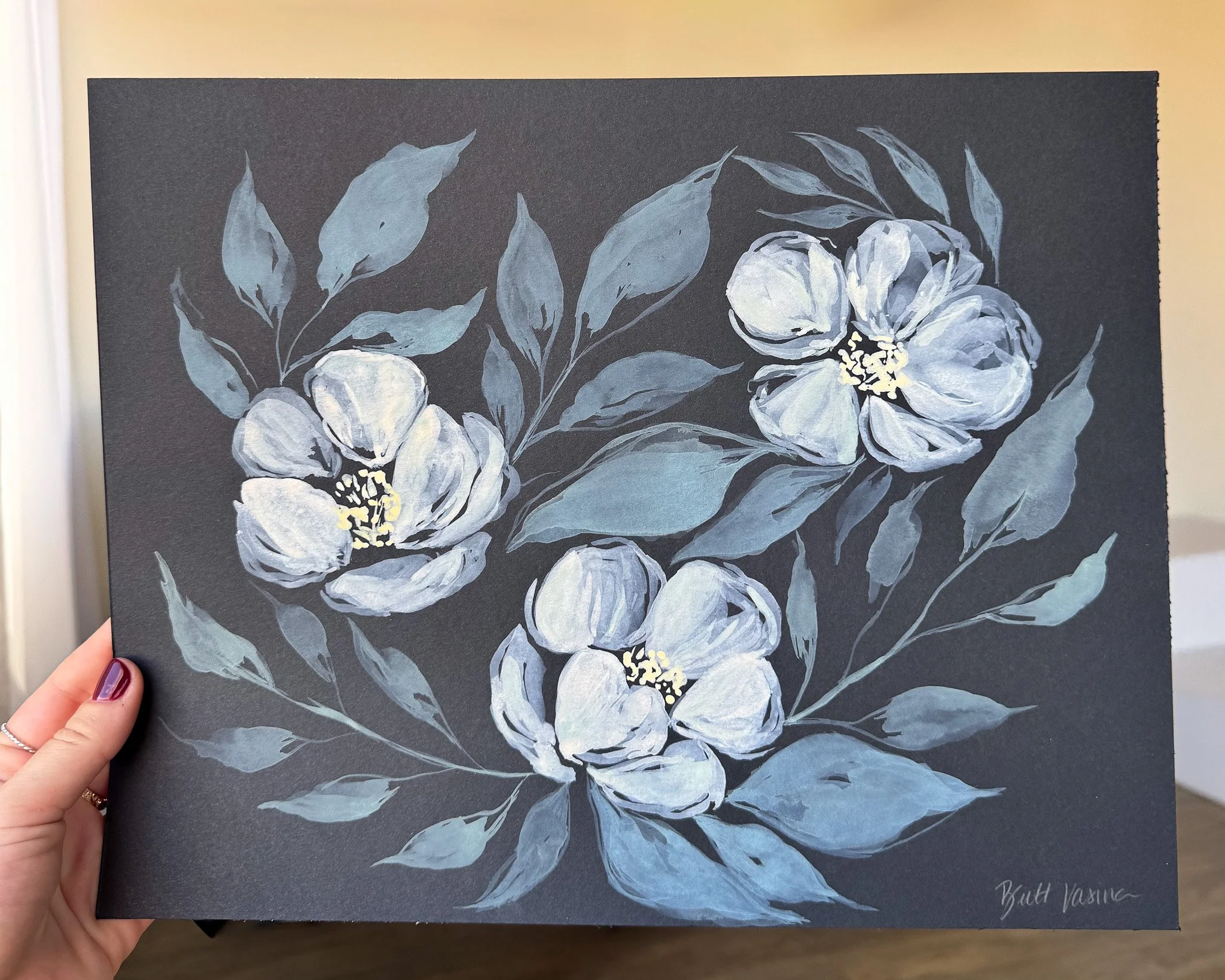 Hand holding an original acrylic floral painting on black paper