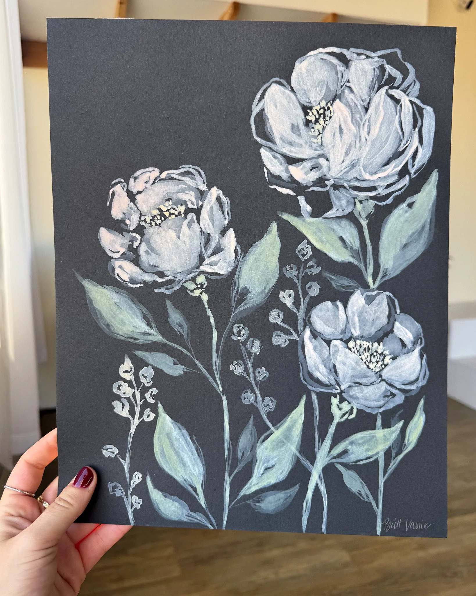 Hand holding an original acrylic floral painting on black paper
