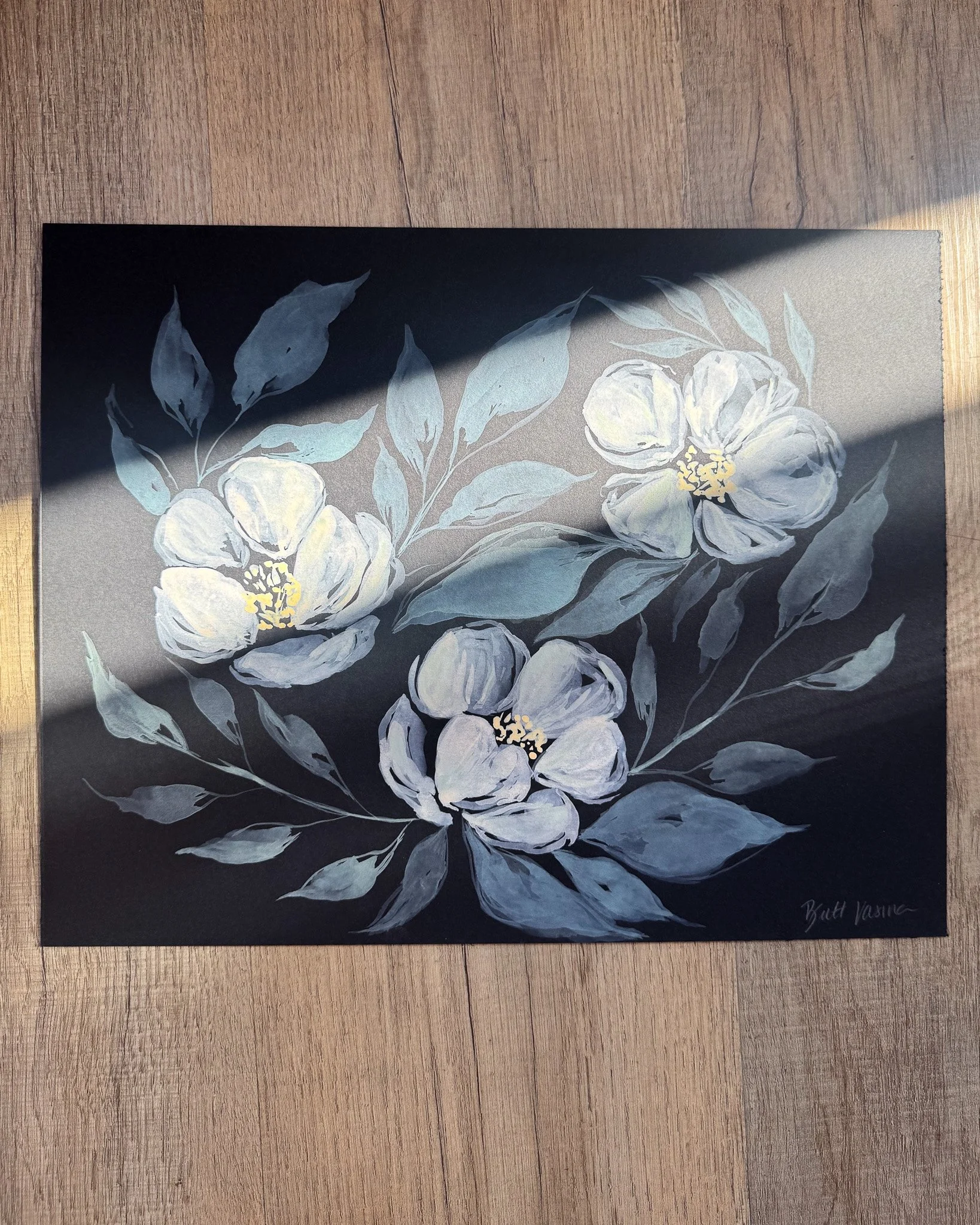 Floral painting on black paper in a beam of sunlight
