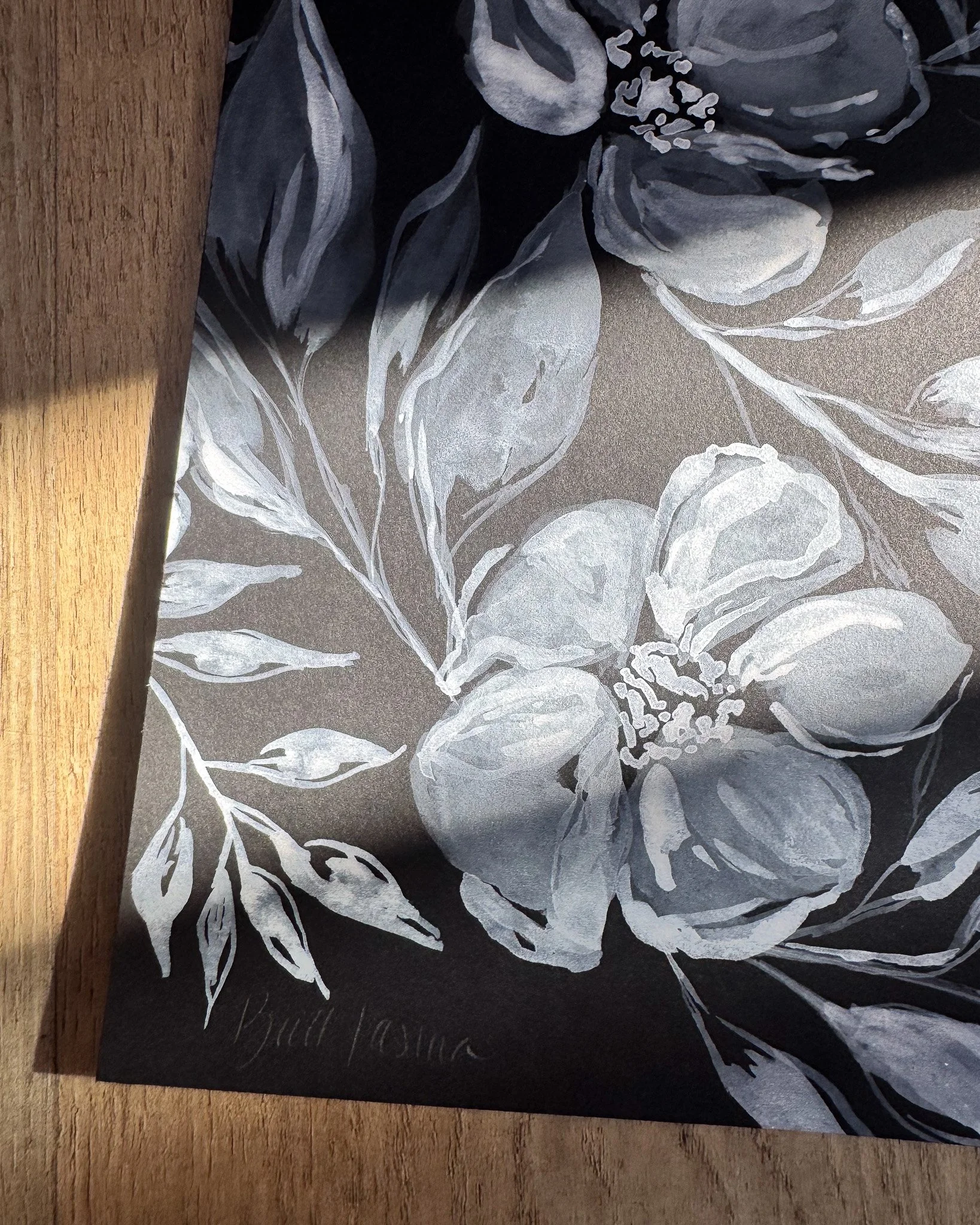 Close-up of white acrylic petals and signature on black paper