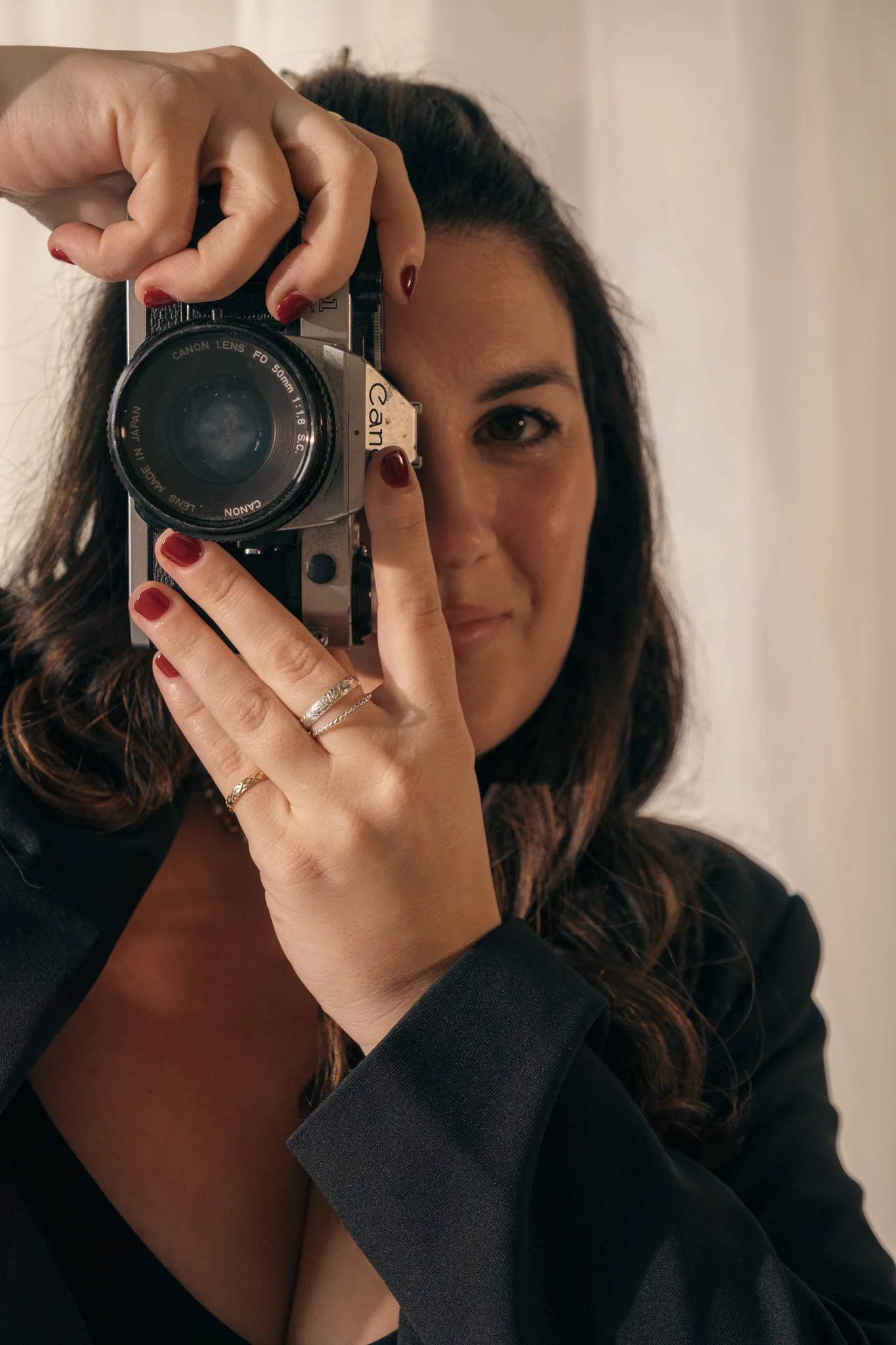 A woman taking a self-portrait with a vintage camera in front of a mirror