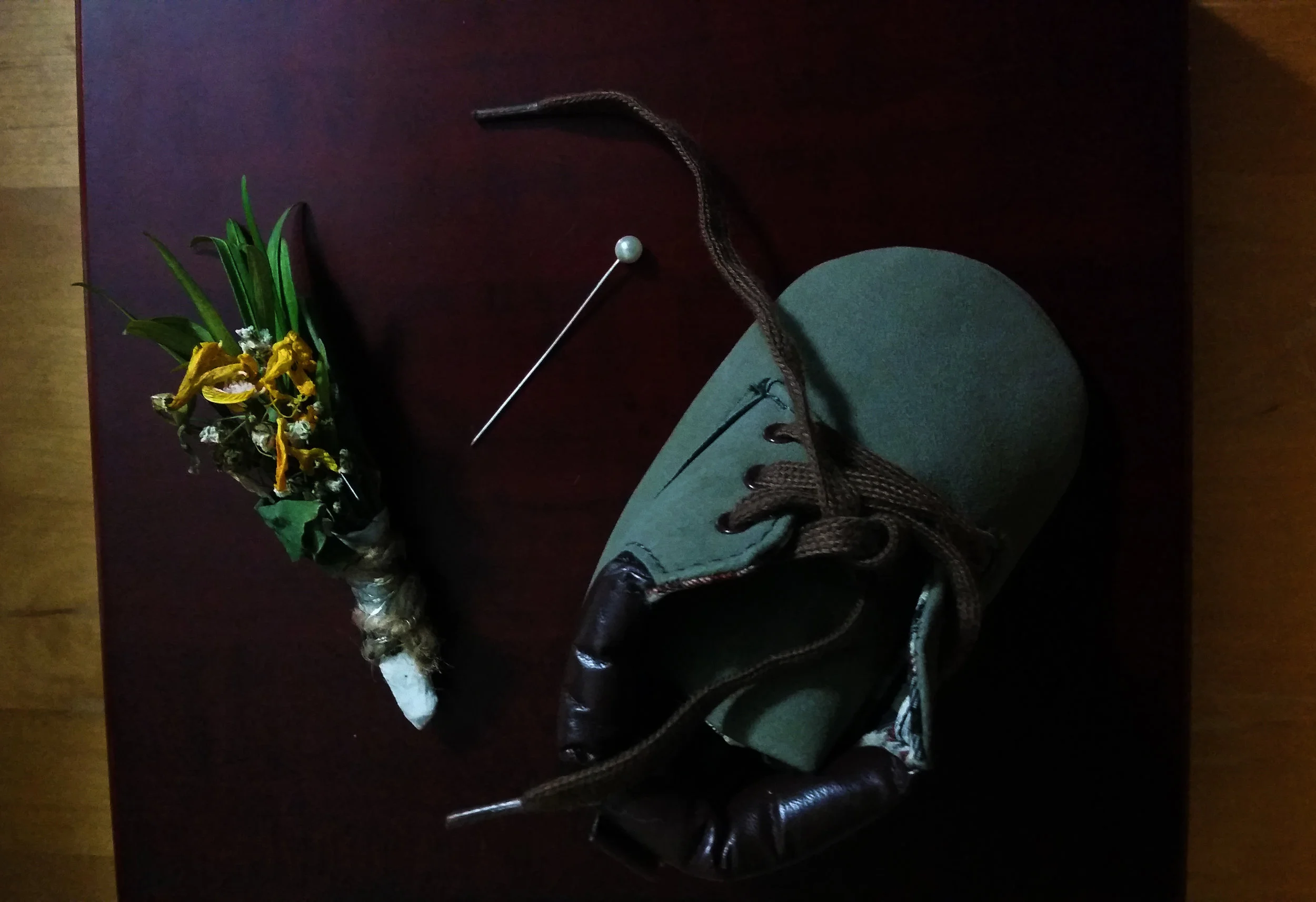 A half-dead boutonniere, a pin, and some blue-swede-baby-shoes. 