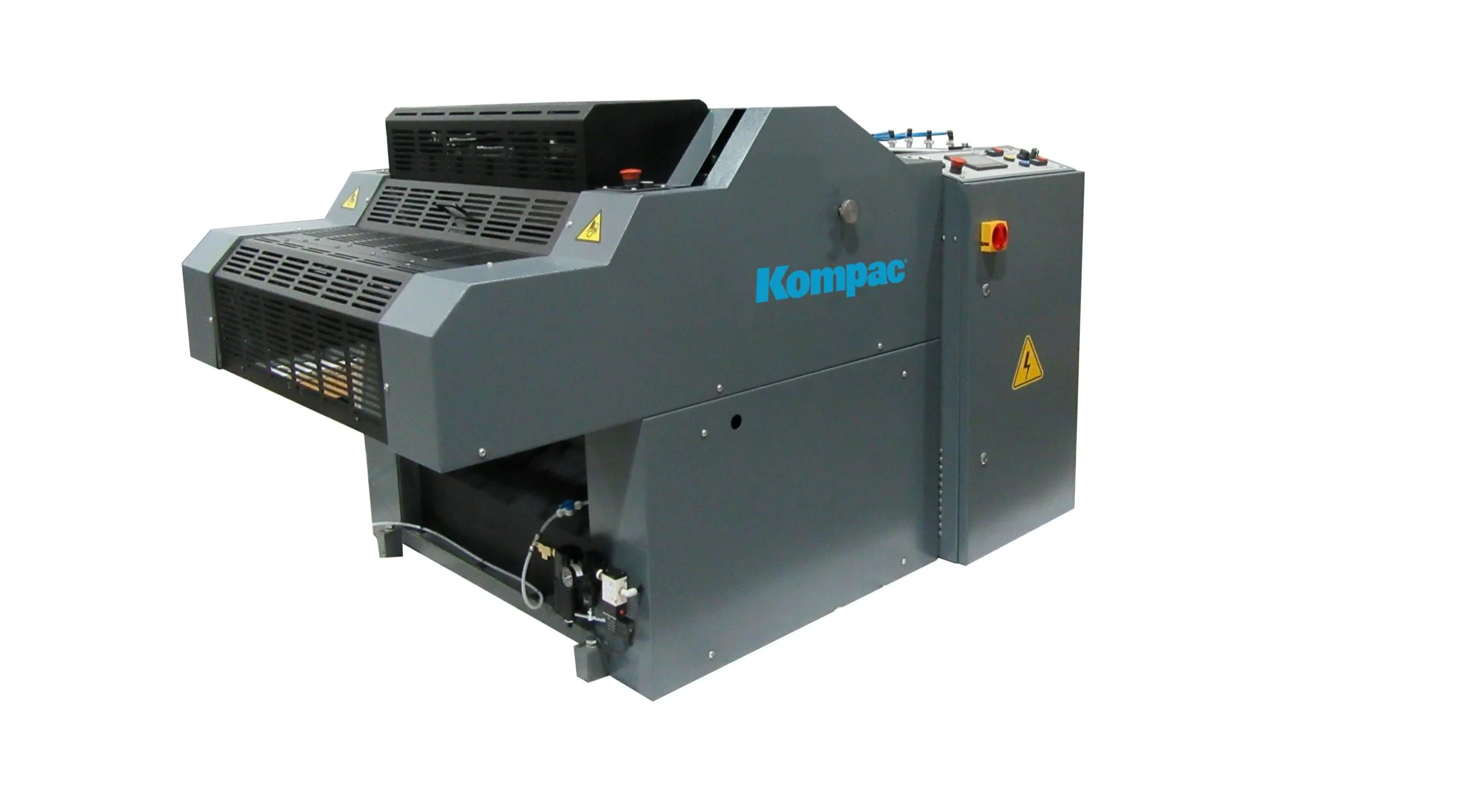 A large gray industrial machine with the brand name 'Kompac' printed on it, featuring vents, control panel, and safety warning labels.