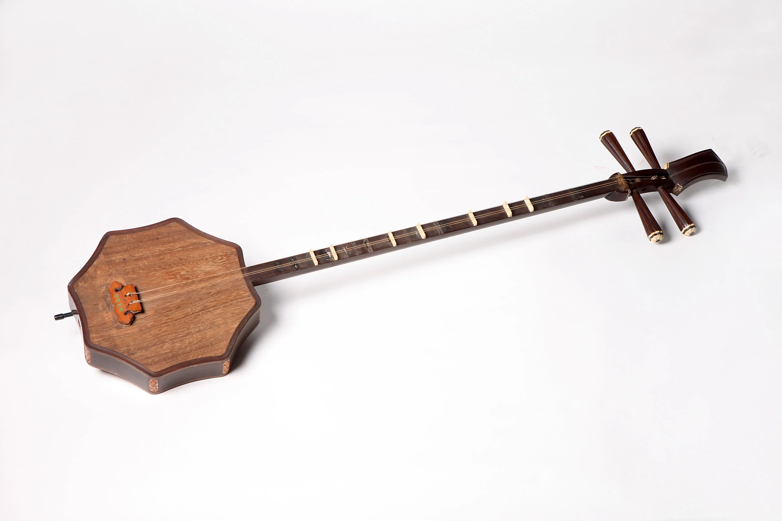 Shuangqing is originated from ruan (Chinese plucked string instrument) with thinner and longer neck than ruan . The sound box of shuangqing is octagon-shaped with four pegs, four strings and thirteen or fourteen frets. According to A Sequel to Wenxian Tongkao in Qing Dynasty (qingchao xu wenxian tongkao) , “ shuangqing is in the ruan family and is an alto instrument. It is three chi and two cun long with an eight- cun deep peg box. Its sound box is one cun and four fen thick. It has three strings, two ranges and thirteen frets and it is played by plucking.”