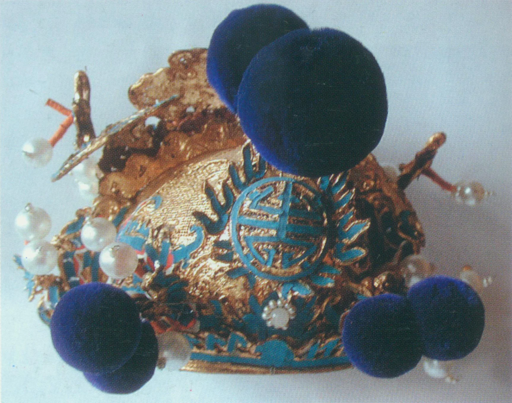 Lotus-Leaf Hat A rigid helmet. It comprises the front and the back parts. Viewing from the font, the hat is fringed with half- ruyi (an S-shaped jade ornament symbolizing good luck) or small cloud patterns. There is a round warped- shou (a Chinese character meaning longevity) encircled flame and a big blue velvet ball at the frontal center. It has a slender dragon on either side and other ornaments such as velvet balls, sea patterns and small dragons, topped by a rigid lotus-leaf-shaped ornament. The back part is slightly higher, and it is decorated with dragons and bats. A pair of wings pointing upwards and some beats and velvet balls are attached to this part. The hat’s body is covered by gold or silver. Qin Qiong wears a lotus-leaf hat in The Kylin Pavilion .