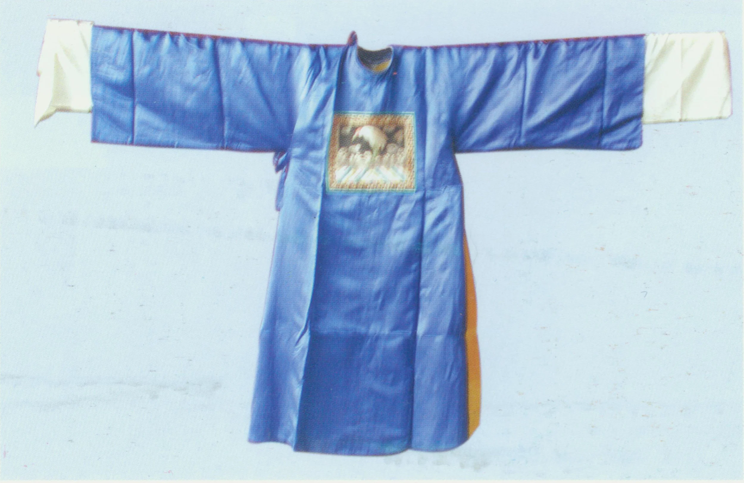Guan yi theatrical clothing for officials, it has rounded necklines and a curved crossover closing tied on the right. It looks similar to mang, but has no embroidery in the fabric. On the back and front chest are Buzi (rank badge for officials) 30cm long and 28cm wide. Buzi has black satin as the background hemmed with floral motifs and geometrical patterns. The upper part of buzi has embroidered sea waves or half of the sun. Birds and beasts are presented in the middle, such as phoenix, peacocks, cranes, dragons, qilins, and leopards. Cloud-shaped motifs are filled with space. The motifs are embroidered with golden or silver threads. Birds in Buzi suggest the rank non-military, and beasts military. The colors of Guanyi, often maroon, purple, blue, are good indicators for the official ranks. The extensions of the robe have a contrasting color, sometimes full of embroidery. Guanyi fabric is satin or tapestry satin. Black Guanyi, or qingsu, has no buzi, and is often worn by menguan (official in service but out of ranking system). There are different types of Guanyi for diffenrent genders. Guanyi for females are shorter with no extensions in the back piece. it is usually red or light olive. The latter is often worn by senior Dan role of high status.