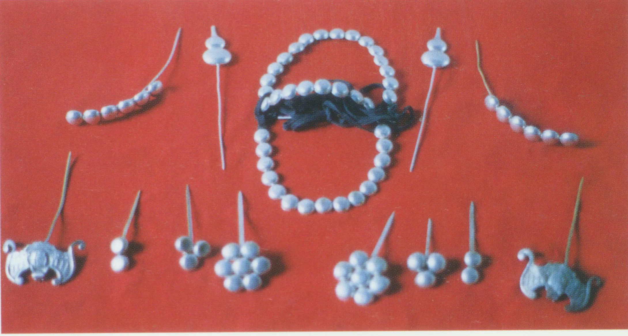 Yinpao toumian headdress for Dan role. It is made of coppery beads with silver plating (Yinpao). Besides small and plum-flower shaped beads, Yinpao toumian has other components like cabalash-shaped and bat-shaped pin, main pin, earrings, and accessories on the temples. According to Accessories of kunqu opera, Bai Suzhen in the story of white snake first staged with Yinpao toumian and headband attached with white bobbles.