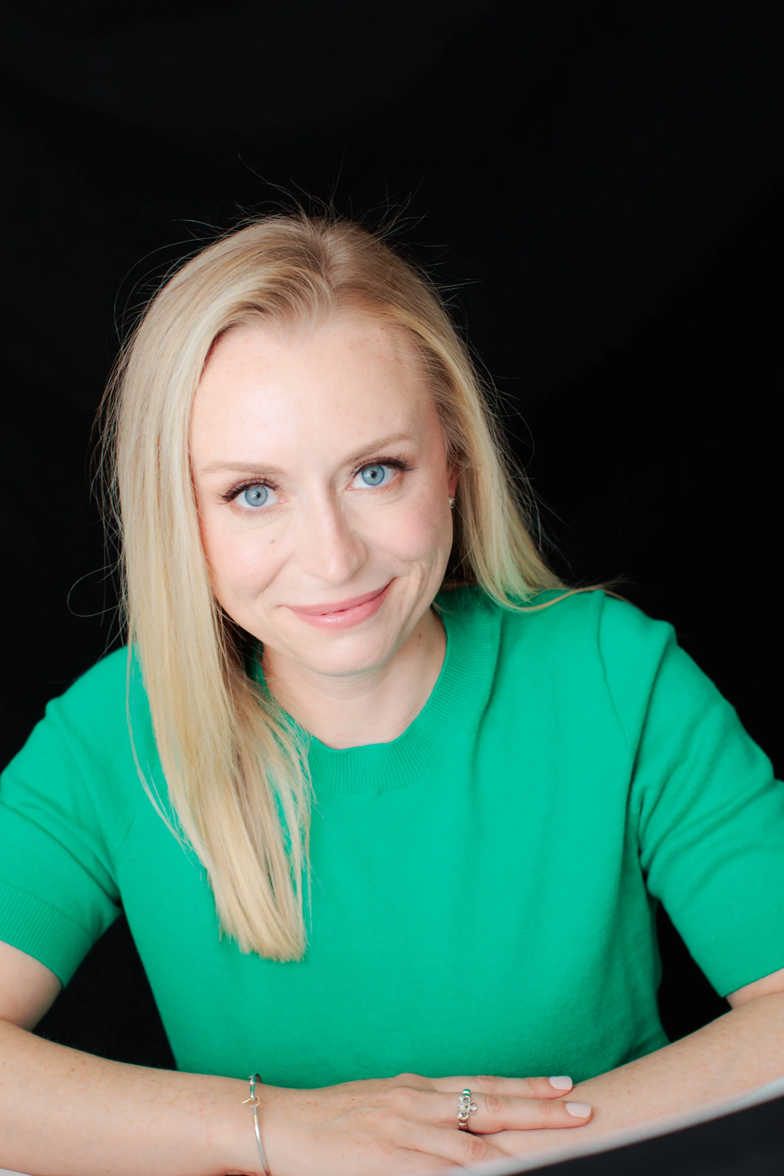 woman in green shirt against a black background for headshot in Silver Spring studio