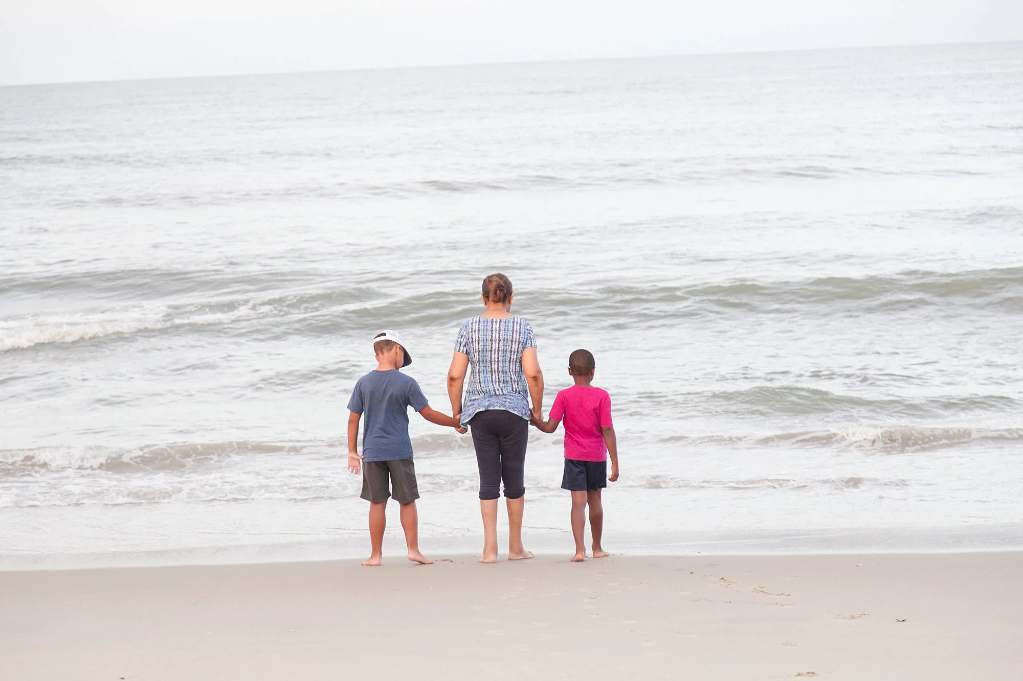 kids standing in ocean with grandmother in Corolla NC