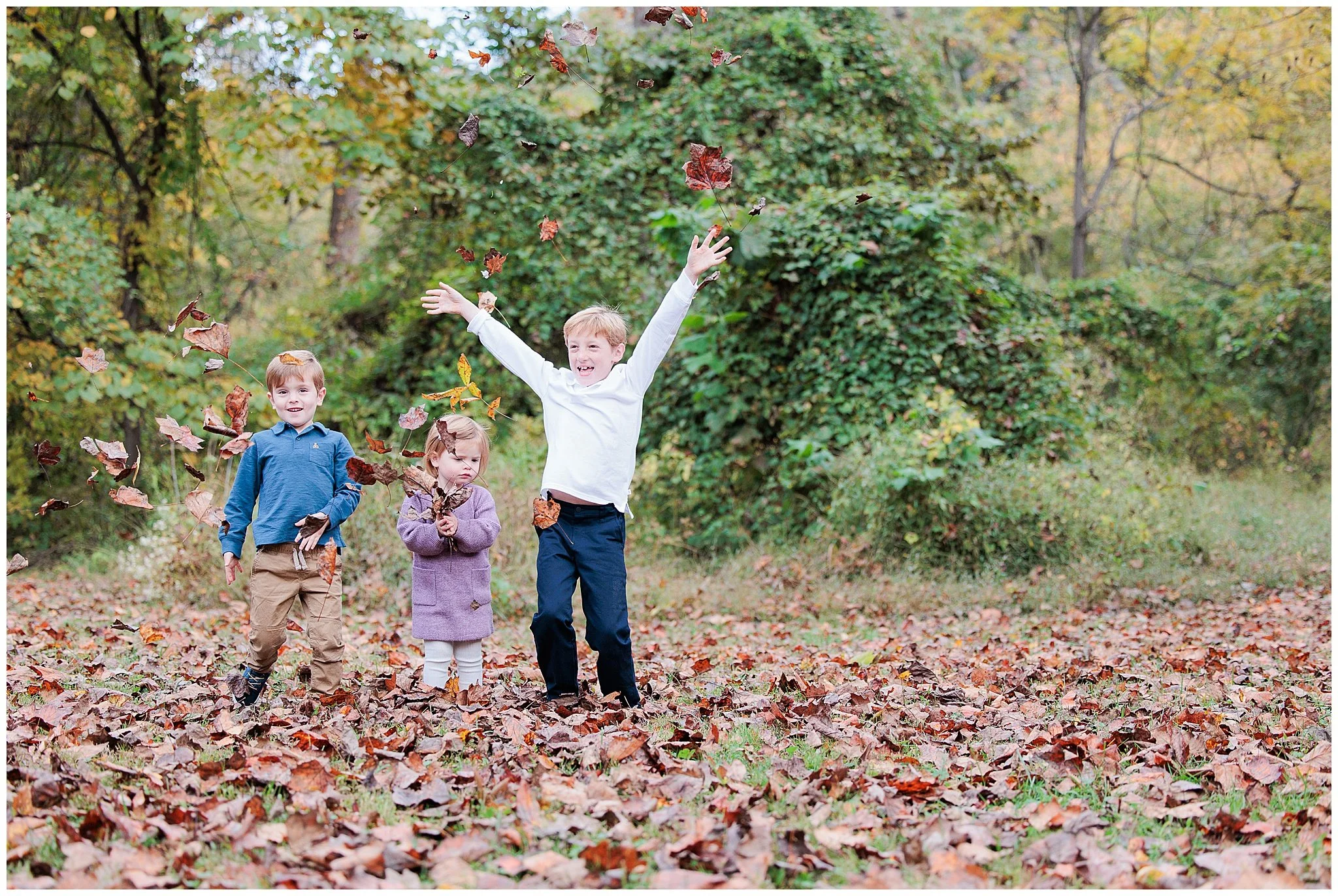 kids throwing leaves during fall family photo session