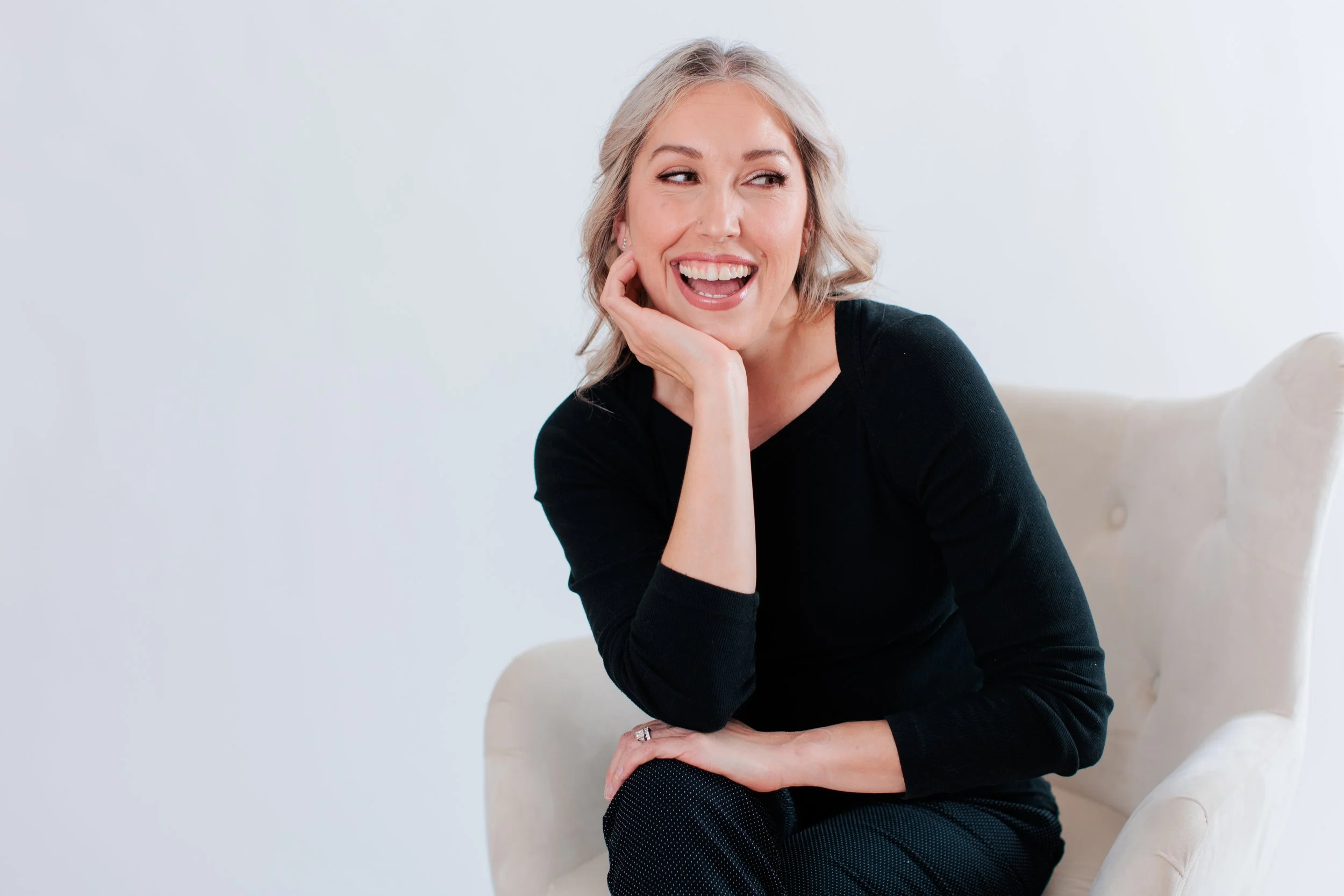 blonde female smiling in a white studio for her headshot