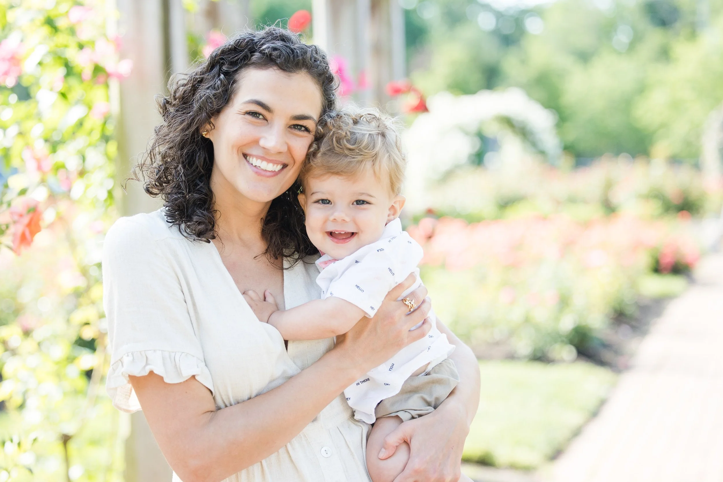 Mother holding toddler during a bright spring family photo session in a garden setting in Arlington VA